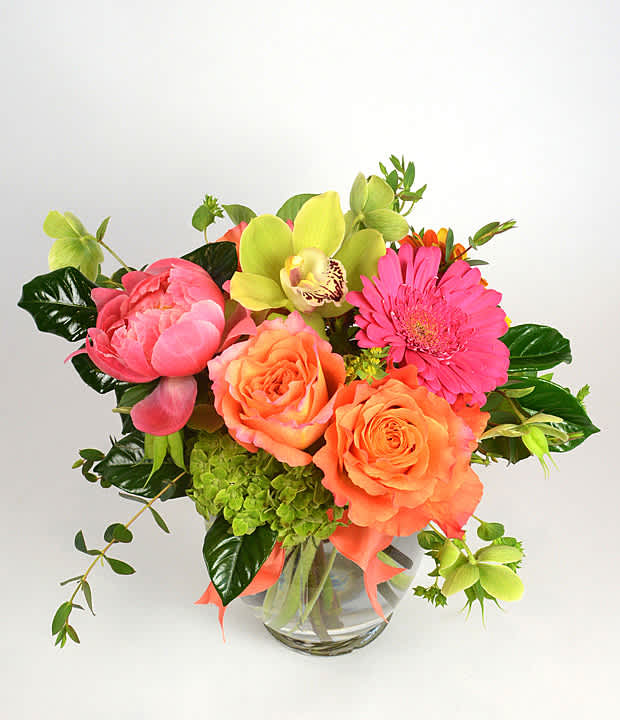 Bouquet of orange roses, pink gerbera daisies, and green orchids in a glass vase
