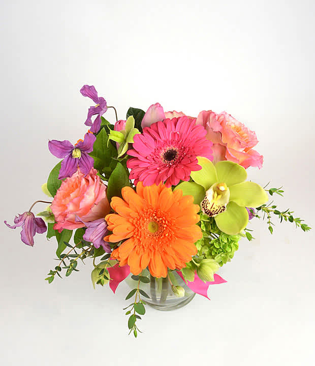 Bright mixed bouquet in a clear glass vase with pink, orange, and purple blooms
