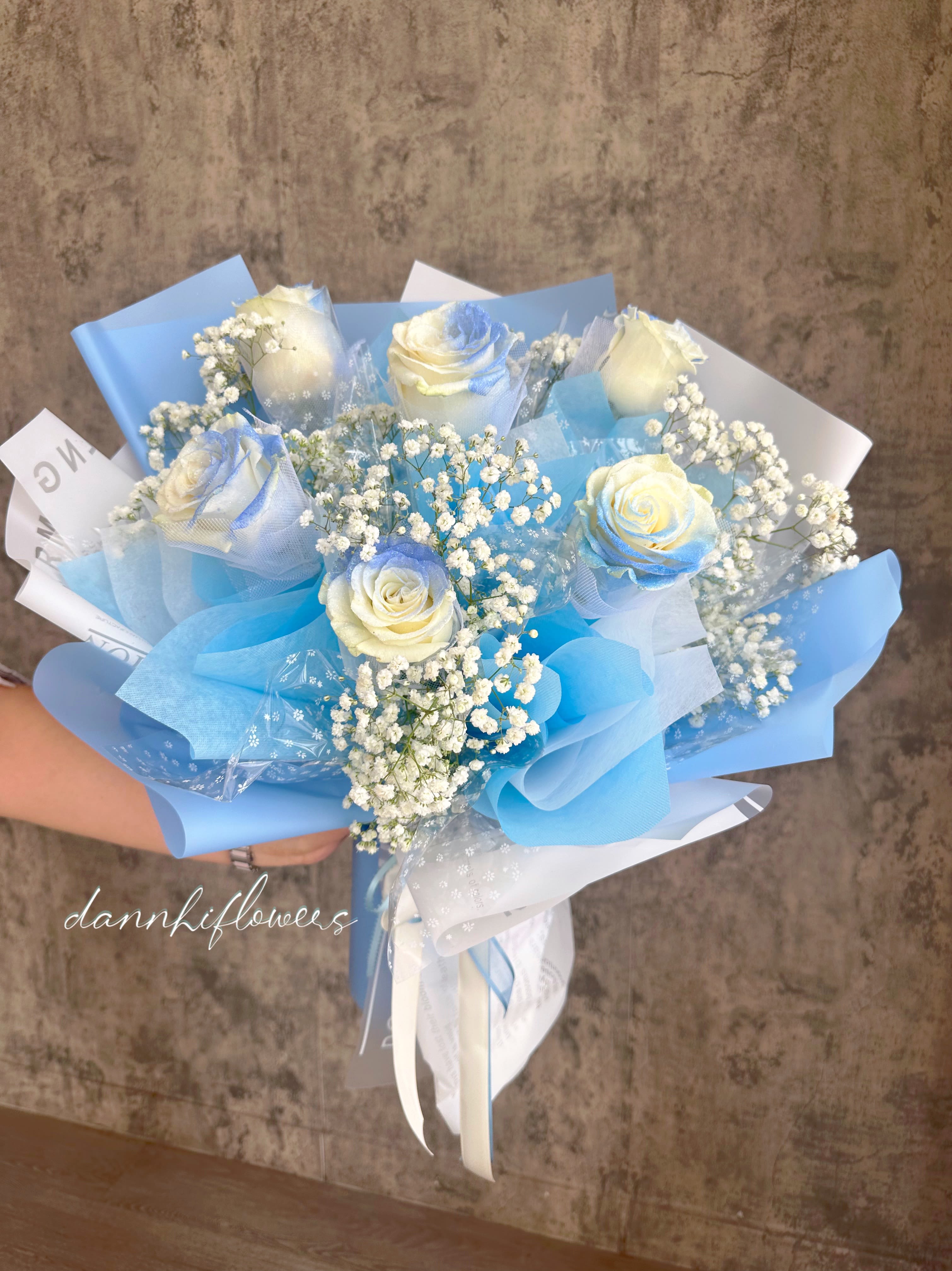 Bouquet of white roses with baby's breath wrapped in blue paper