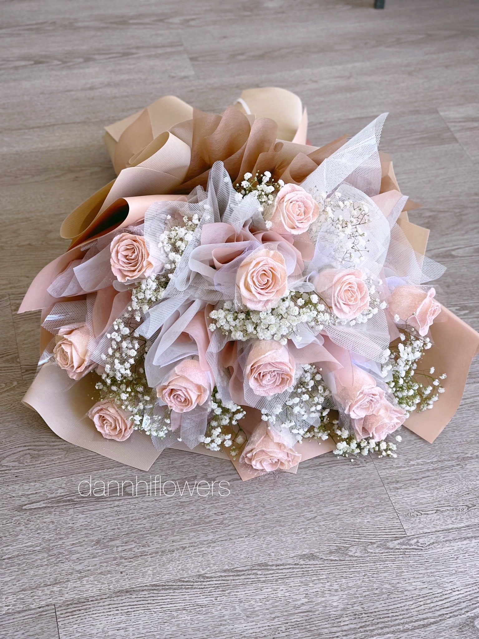 Bouquet of pale pink roses with white baby's breath in blush and beige wrap