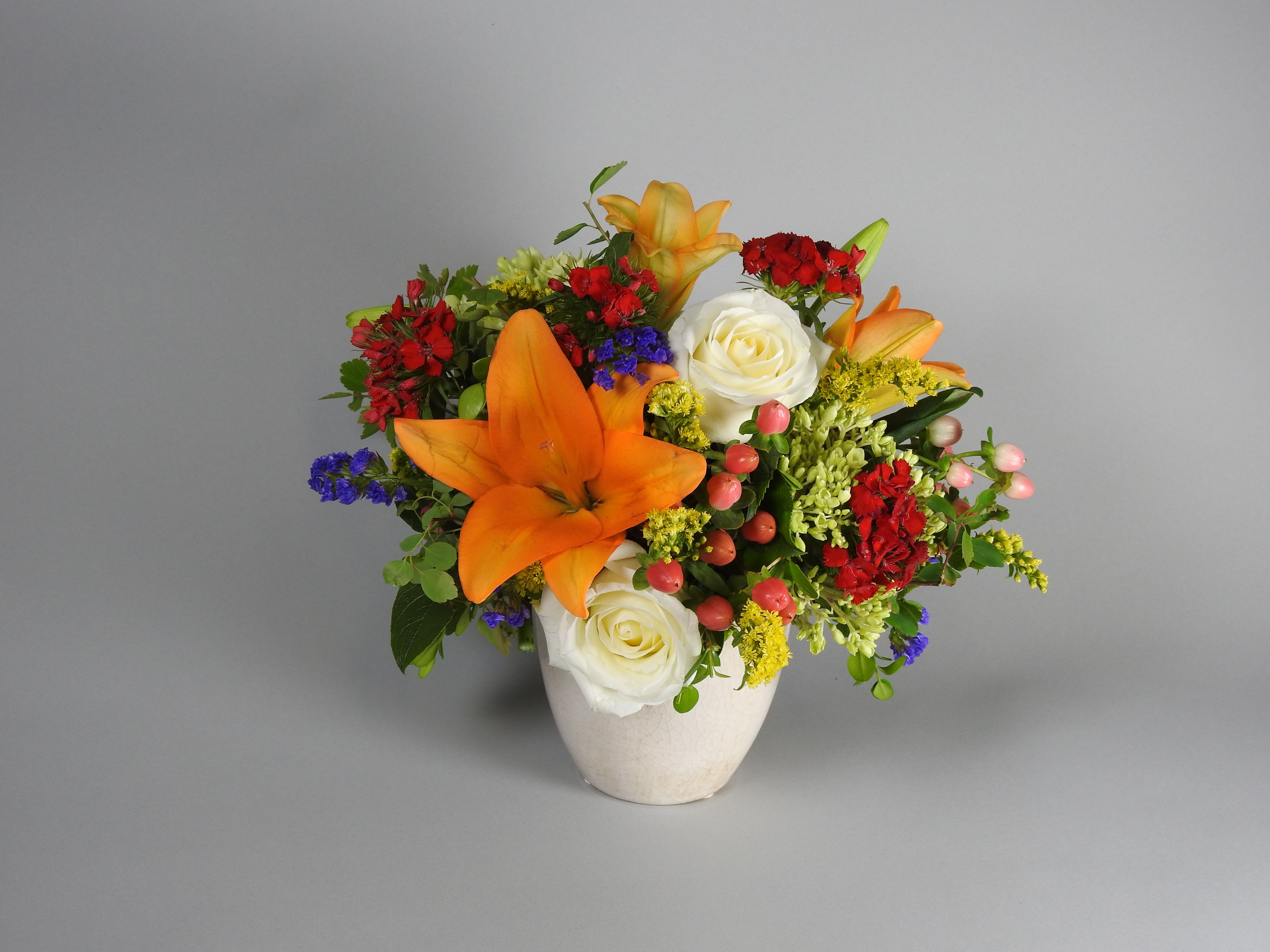Orange lilies and white roses in a white vase