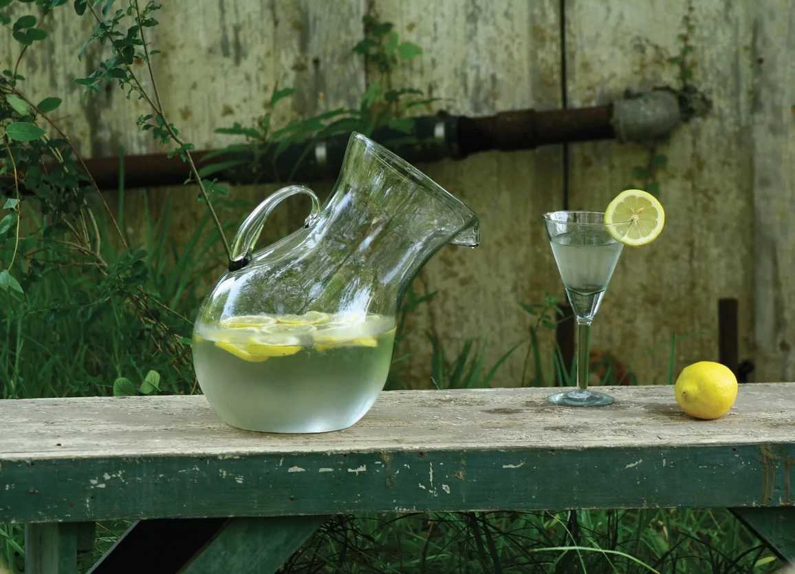 Large Glass Tilted Pitcher - Equally suited to either endeavor, our glass tilted pitcher is hand-blown by Colombian artisans. Bubbles and slight imperfections in the glass are natural and add to its charm. 8" x 12"t
