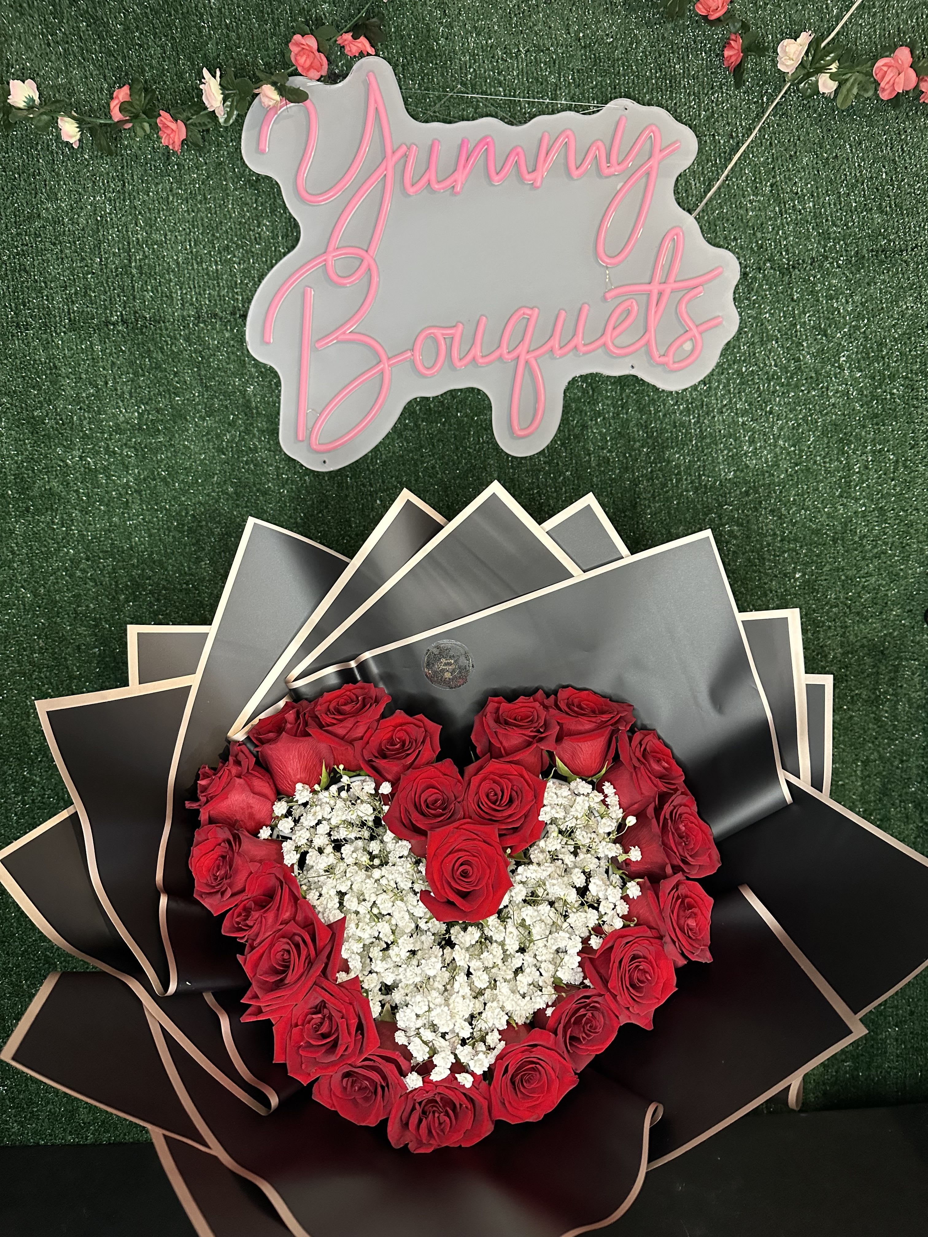 Heart-shaped red rose bouquet with white baby's breath and black wrapping