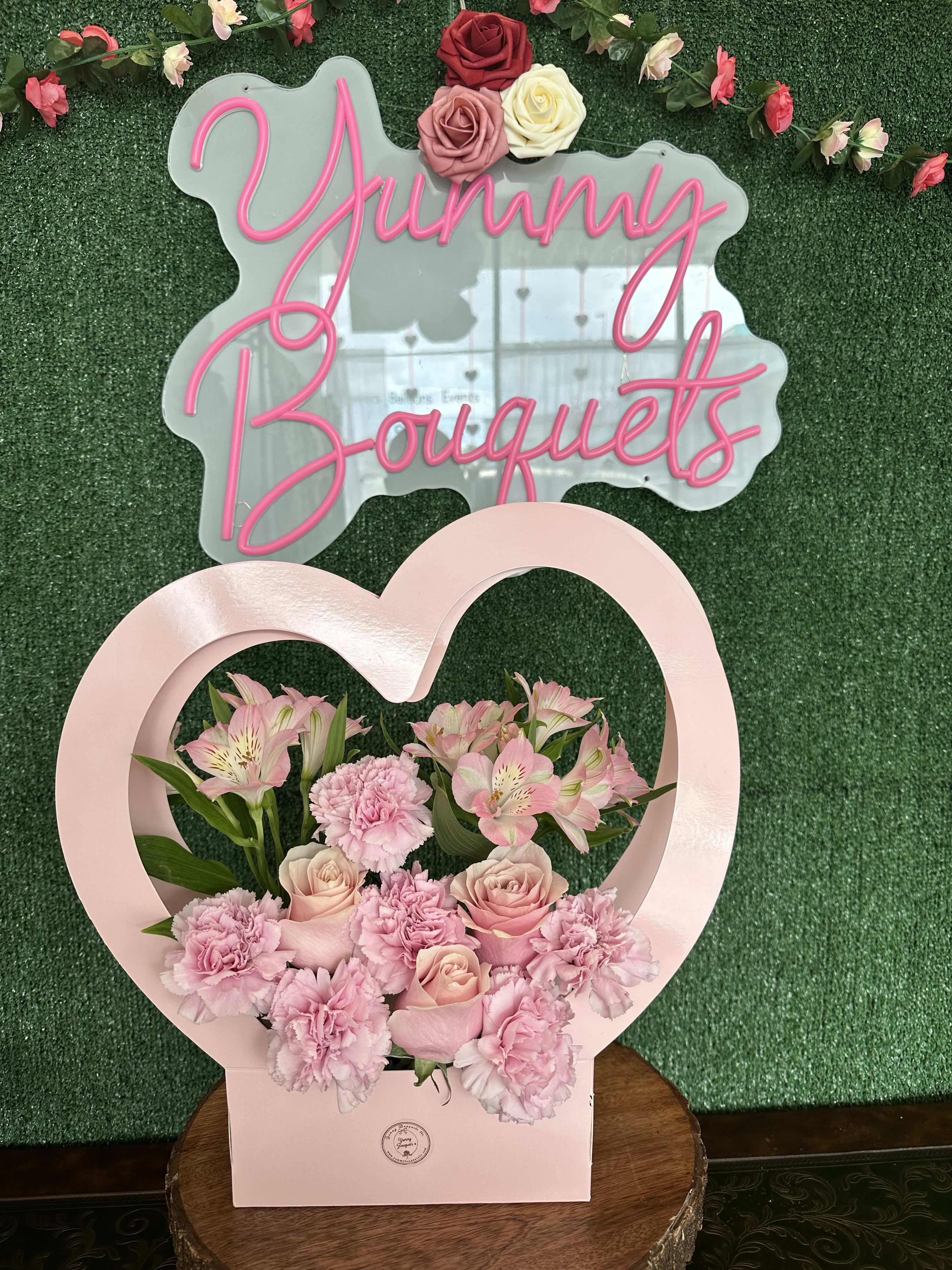 Pink floral arrangement in a heart-shaped box with roses and carnations