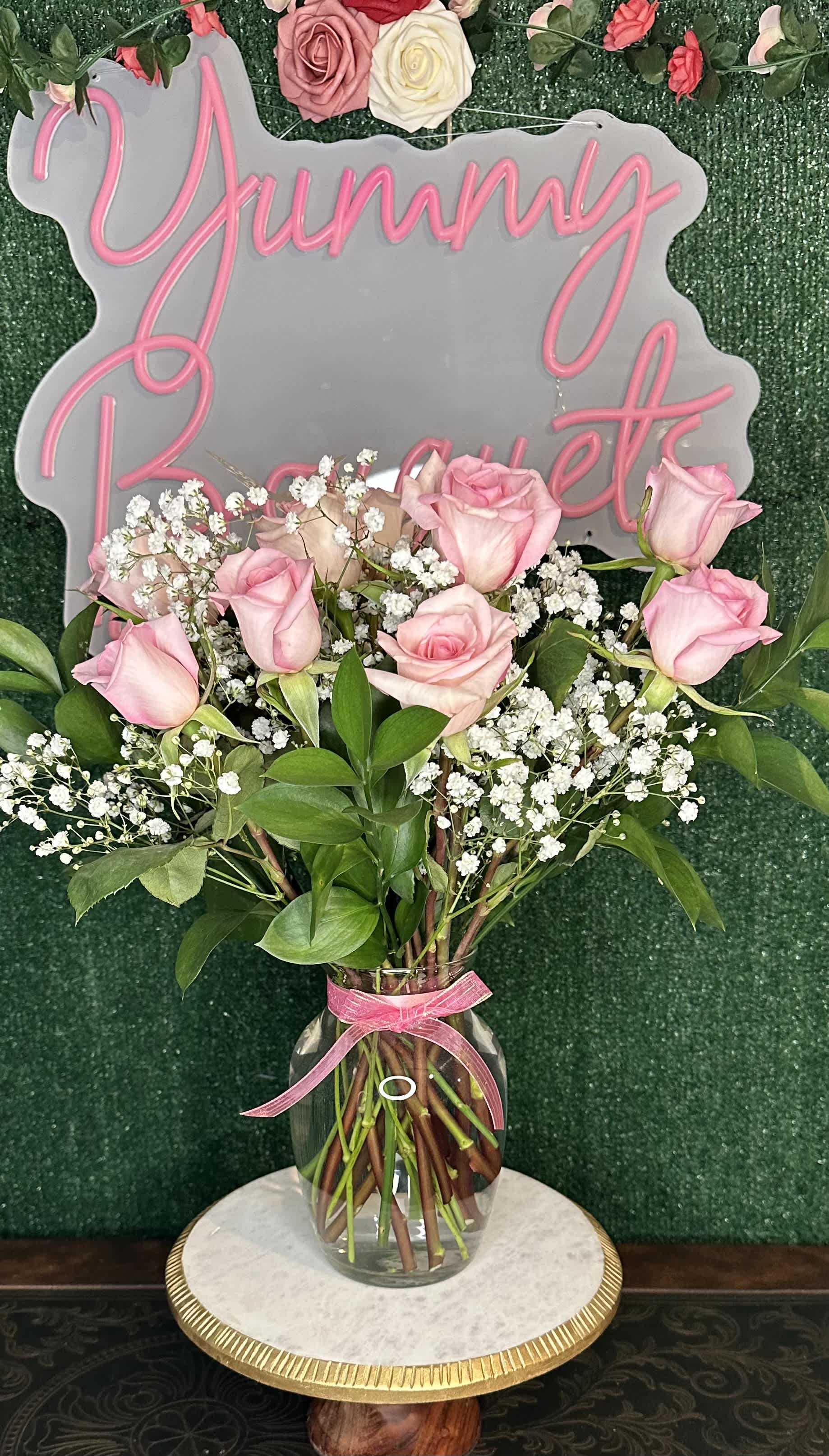 Pink roses and baby's breath in a clear vase with a pink ribbon