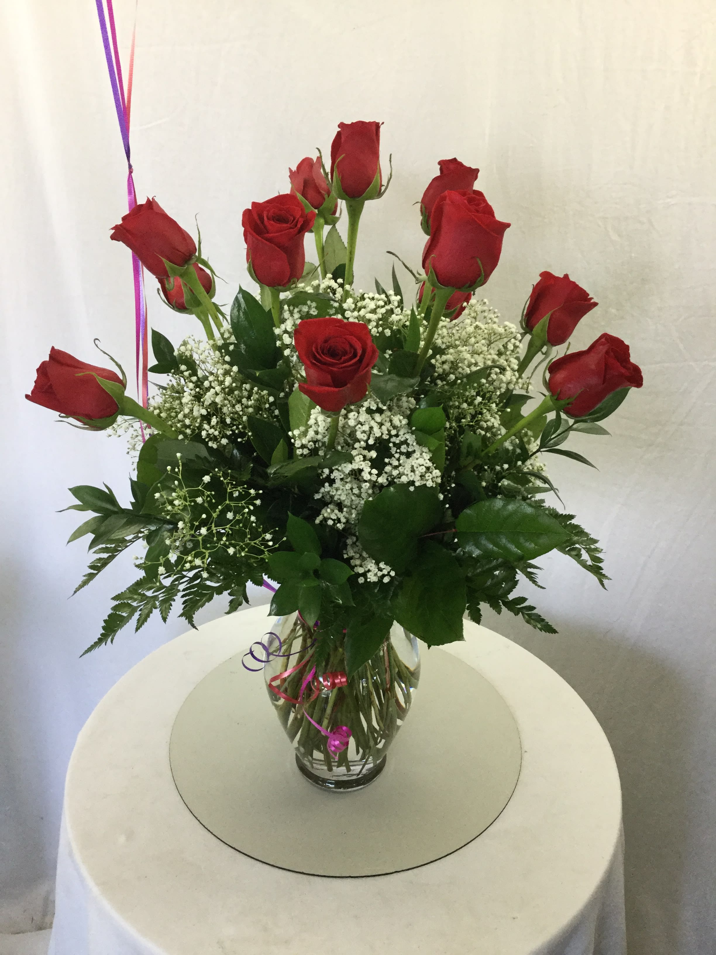 Red roses arranged in a clear glass vase with white filler flowers