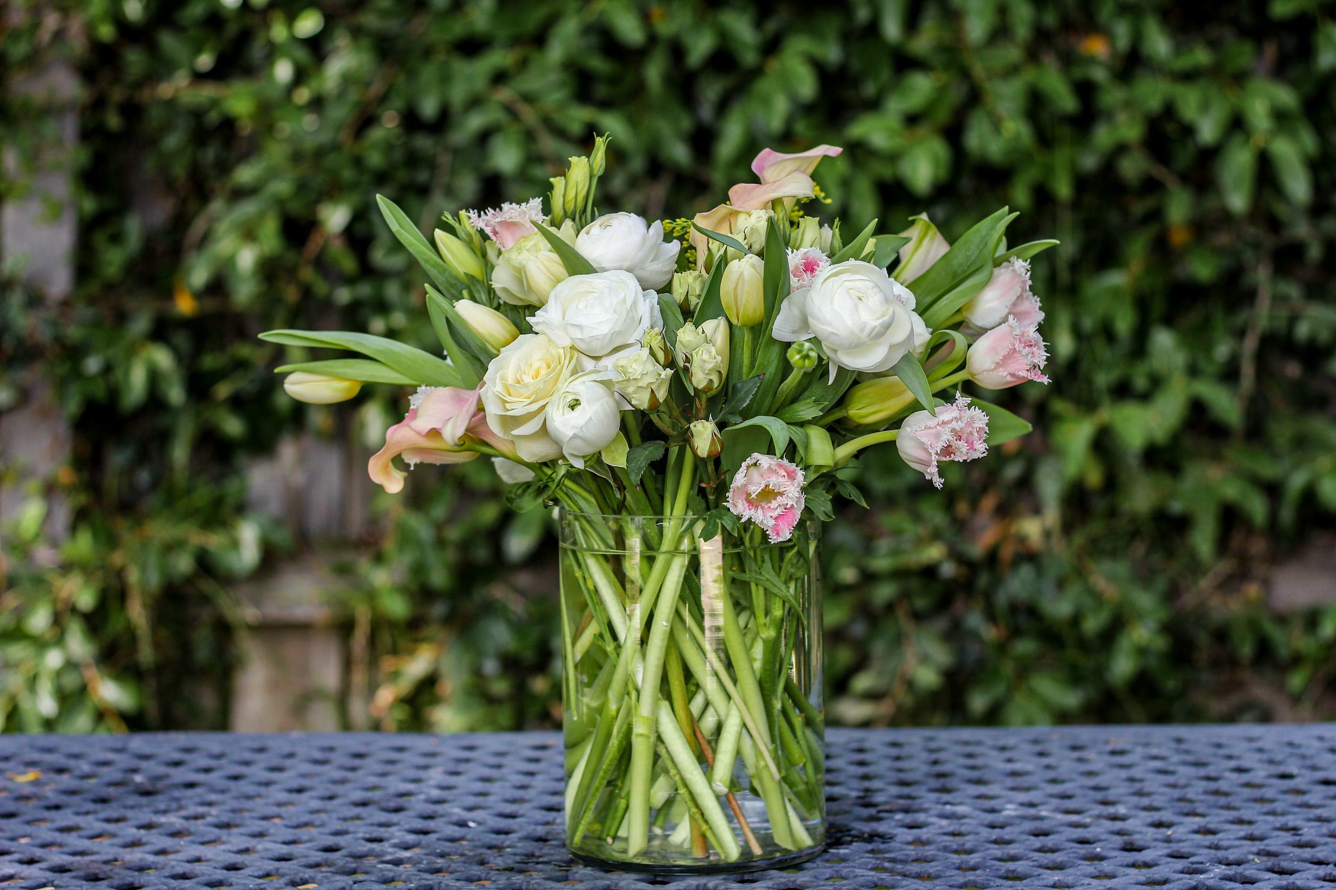 White and pale pink flowers arranged in a clear glass vase