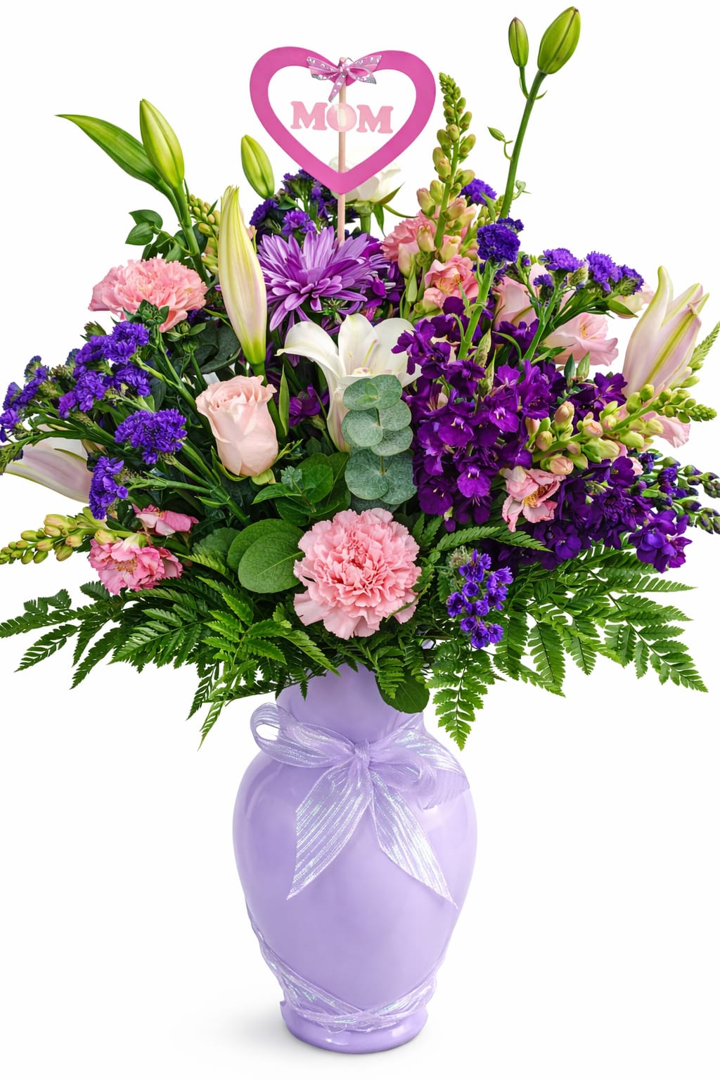 Melbourne Love Bouquet - Celebrate Mom with a gift as beautiful and heartfelt as she is. The MOM’s Motherly Love Bouquet features a lush, garden-style arrangement of soft pinks, rich purples, and elegant whites, including roses, lilies, carnations, and seasonal blooms, all accented with fresh greenery.  Designed in a charming lavender keepsake vase tied with a delicate ribbon, this arrangement is topped with a sweet pink heart “MOM” pick—adding a thoughtful finishing touch. Pick style may vary based on availability.  Whether for Mother’s Day or just because, this bouquet delivers warmth, gratitude, and a touch of elegance straight to her door.  Perfect for: Mother’s Day, birthdays, or simply saying “I love you, Mom.”