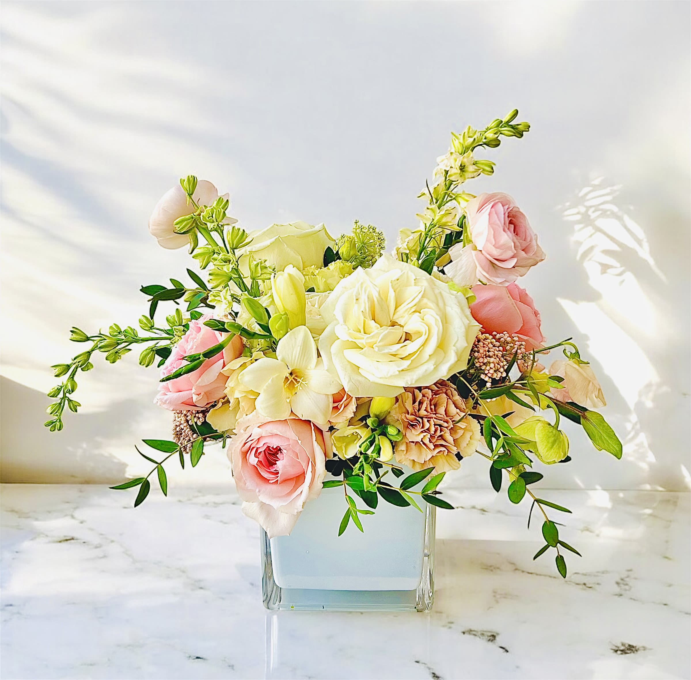 Pink and white roses arranged in a clear square vase
