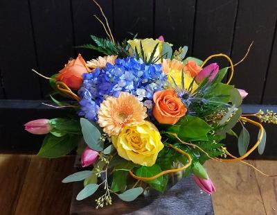 Colorful bouquet with blue hydrangea, roses, and tulips in a glass vase