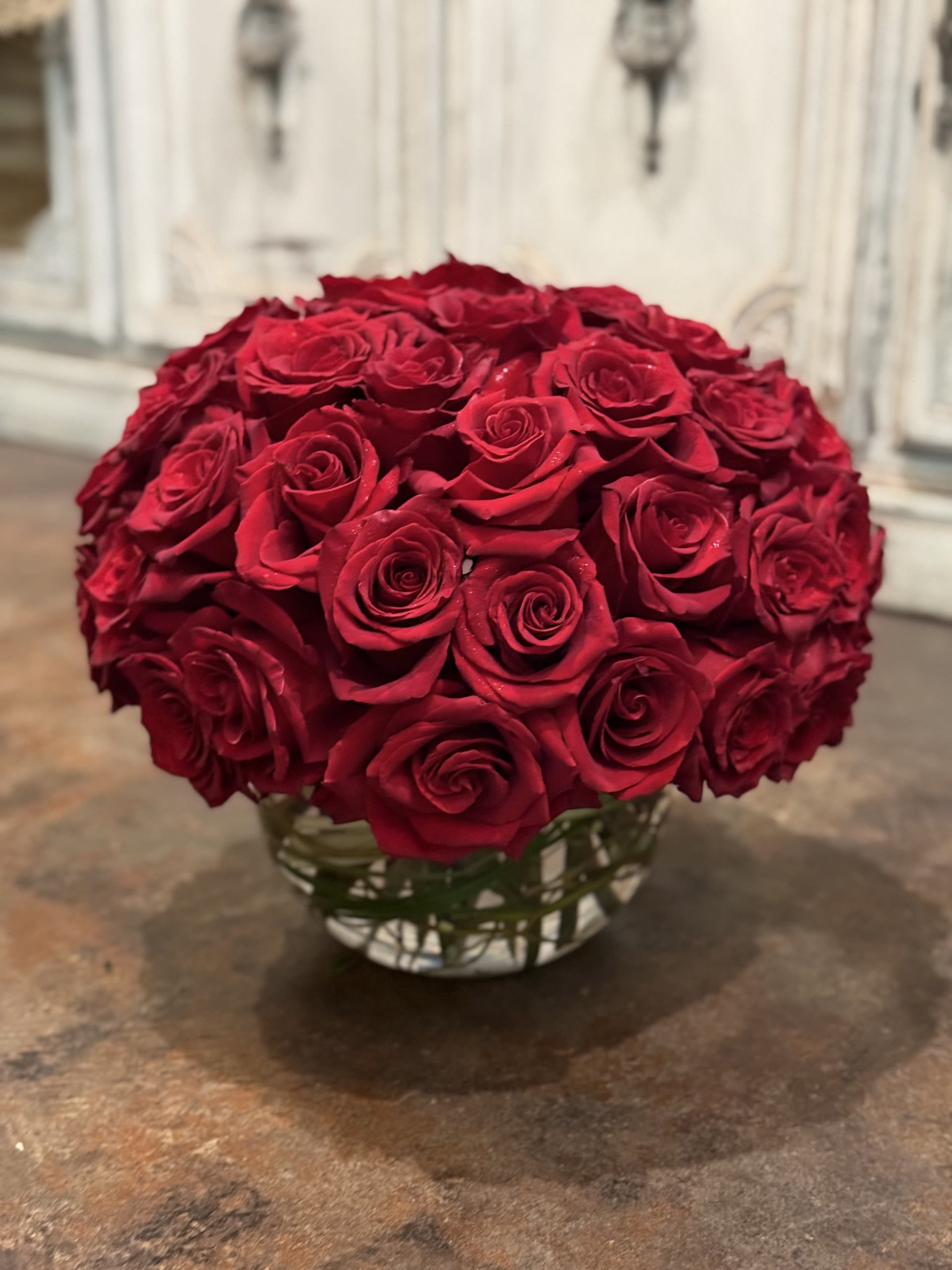 Round bouquet of red roses in a clear glass vase