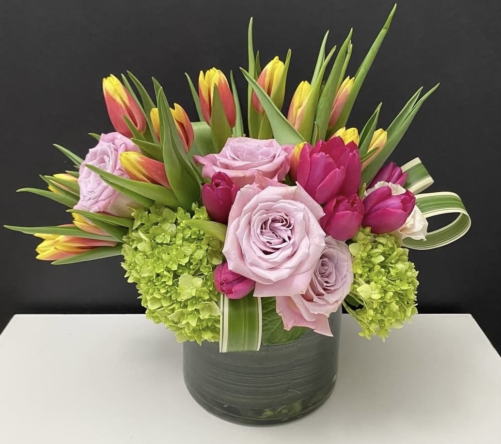 Low glass vase arrangement of pink roses, tulips, and green hydrangeas.