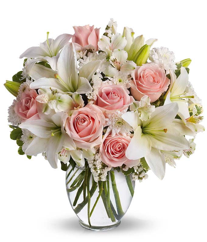 Pink roses and white lilies arranged in a clear glass vase