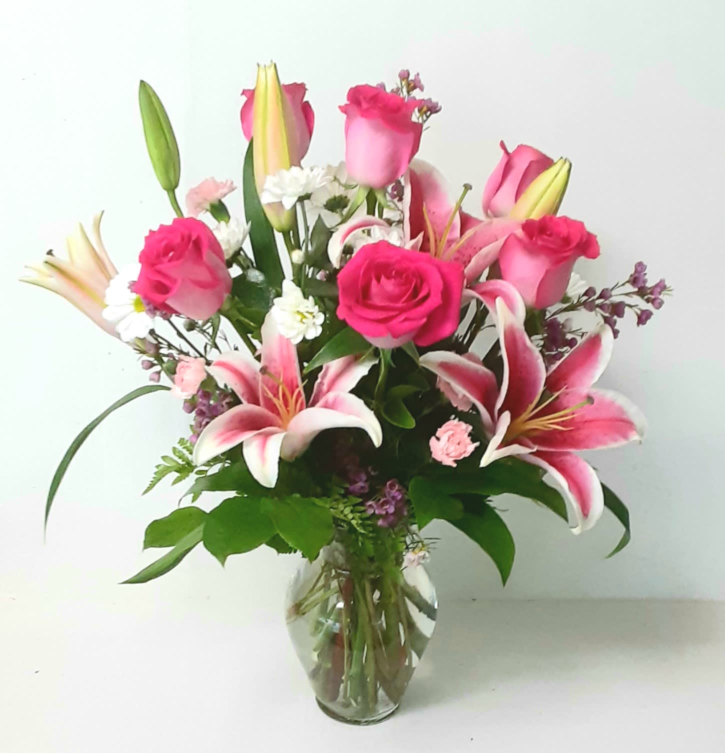 Pink roses and lilies arranged in a clear glass vase
