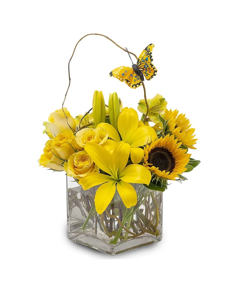 Yellow floral arrangement in a square glass vase with a butterfly pick