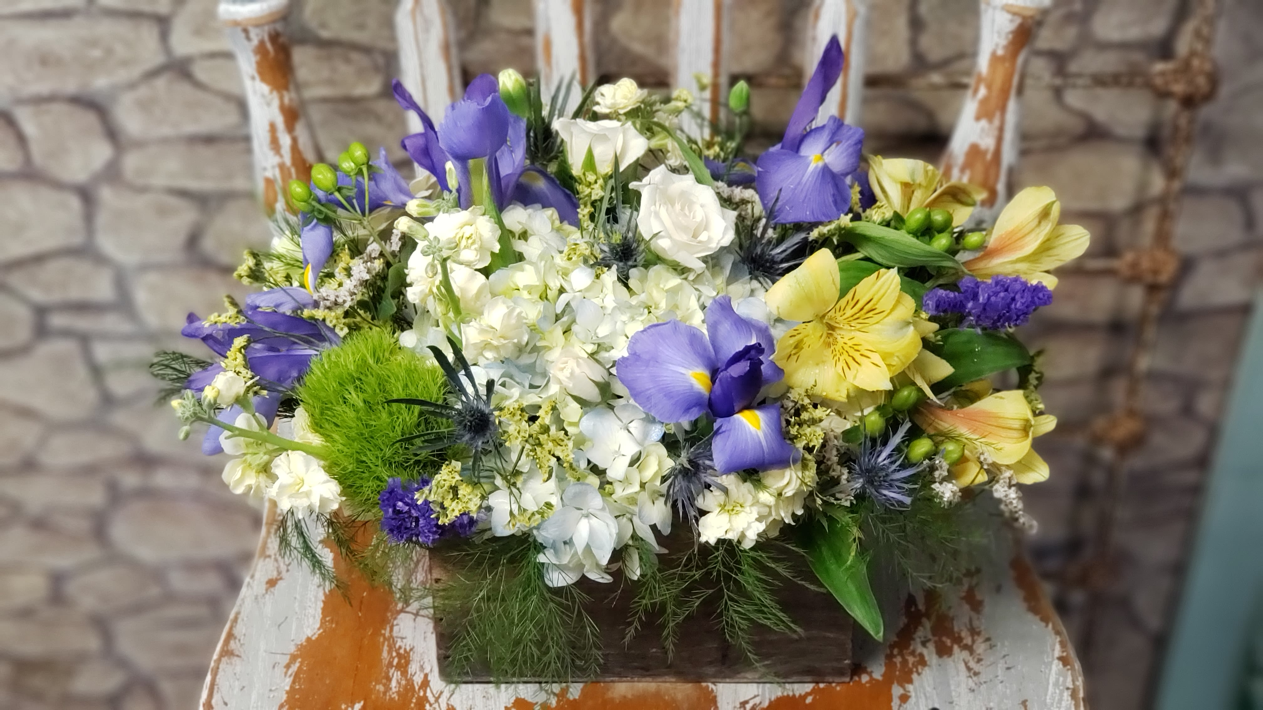 Mixed bouquet of purple, white, and yellow flowers in a wooden box