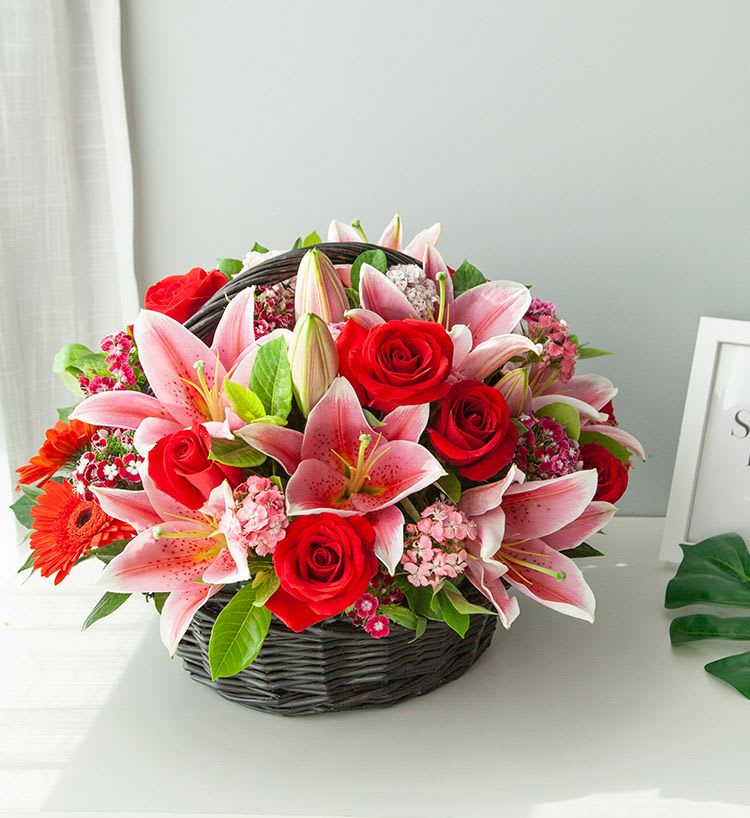 Basket arrangement of pink lilies and red roses