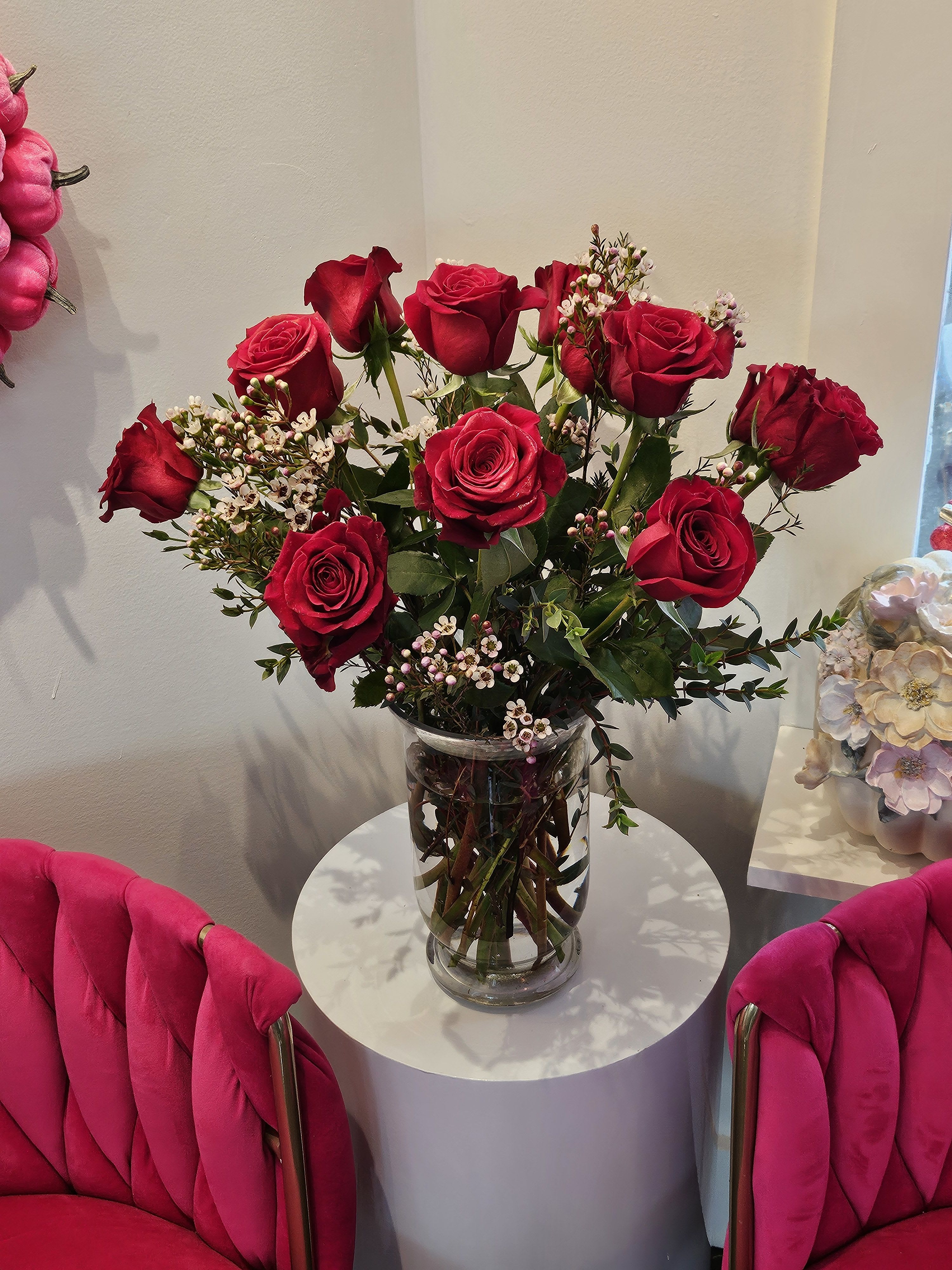 Red roses arranged in a clear glass vase on a small round table