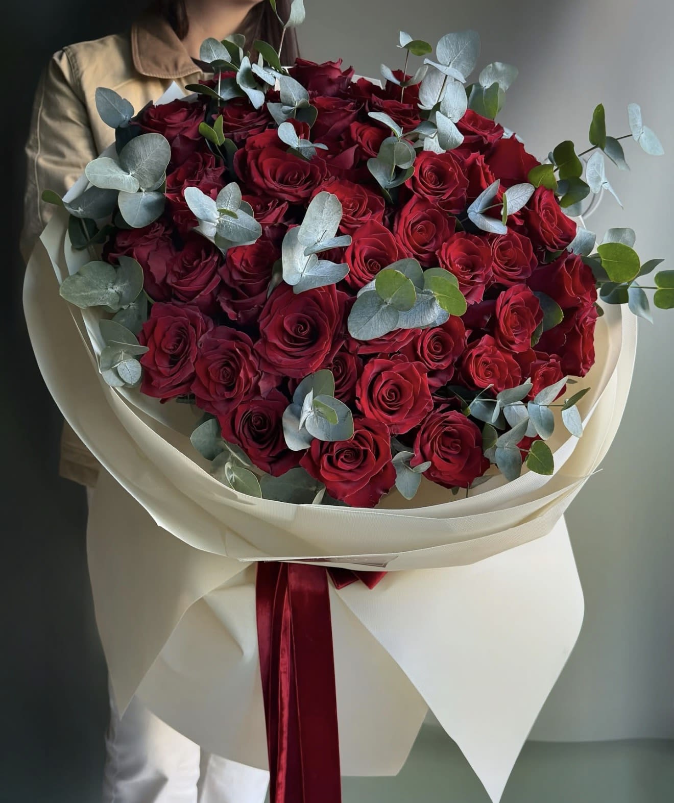 Bouquet of red roses with eucalyptus in cream wrapping