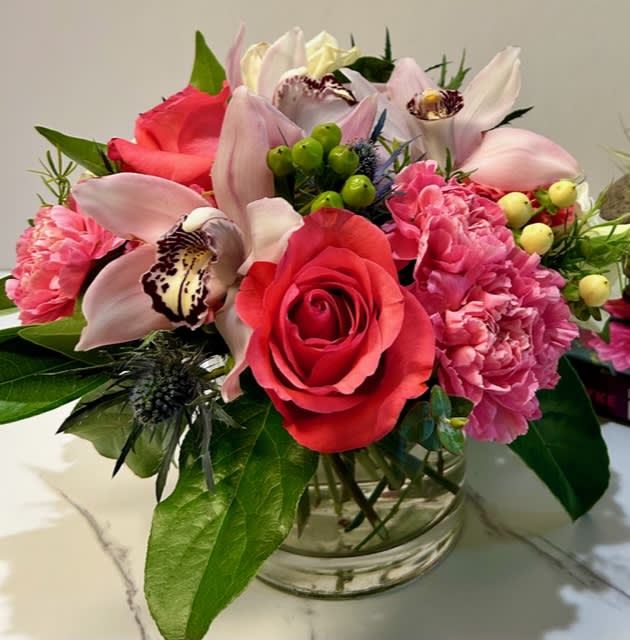 Bouquet of pink roses, orchids, and carnations in a glass vase