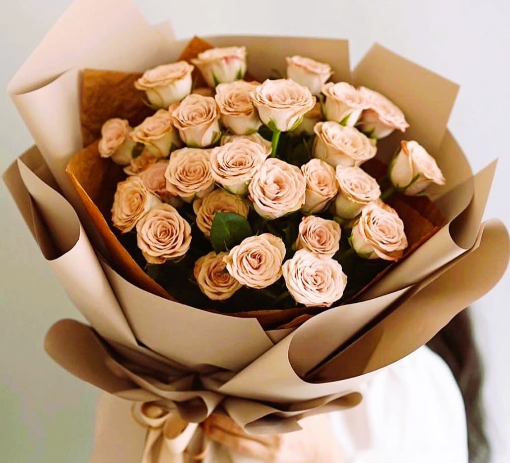 Bouquet of pale peach roses wrapped in brown paper