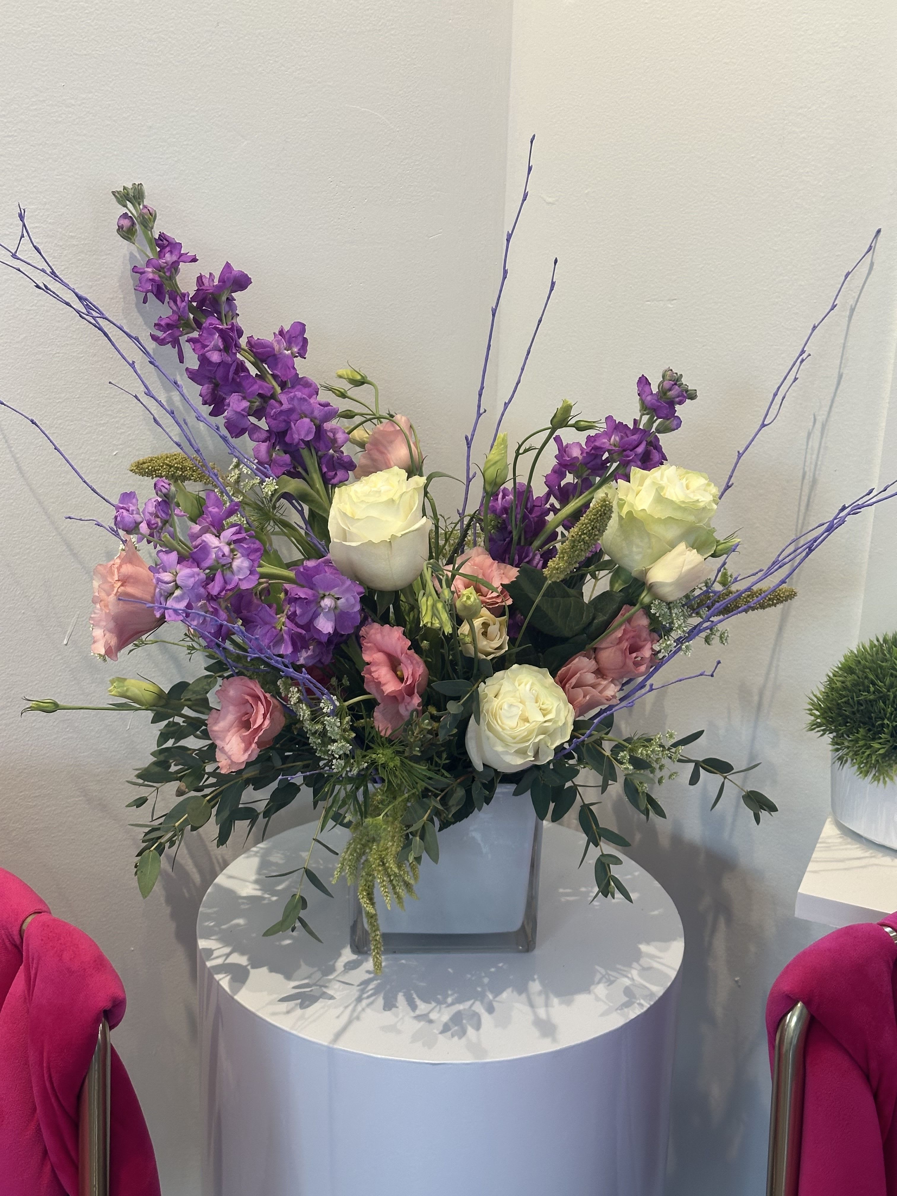 Purple and pink floral arrangement in a square vase with long branches