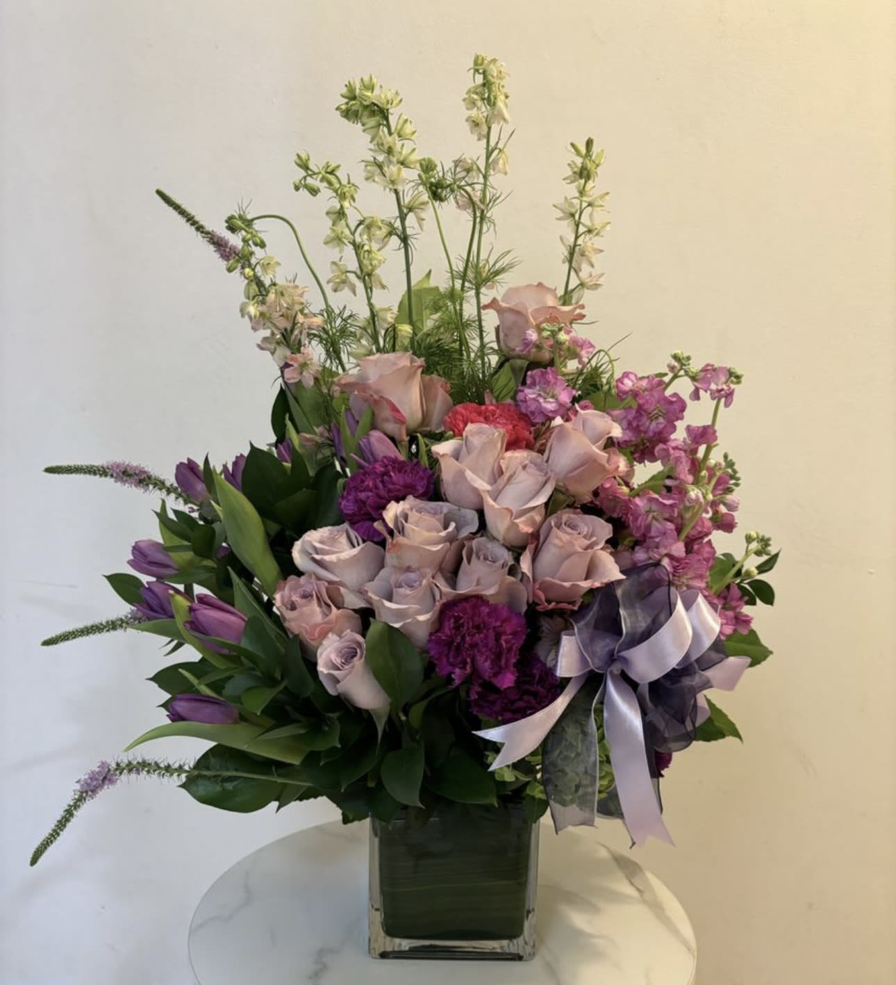 Lavender and pink floral arrangement in a square glass vase with a ribbon