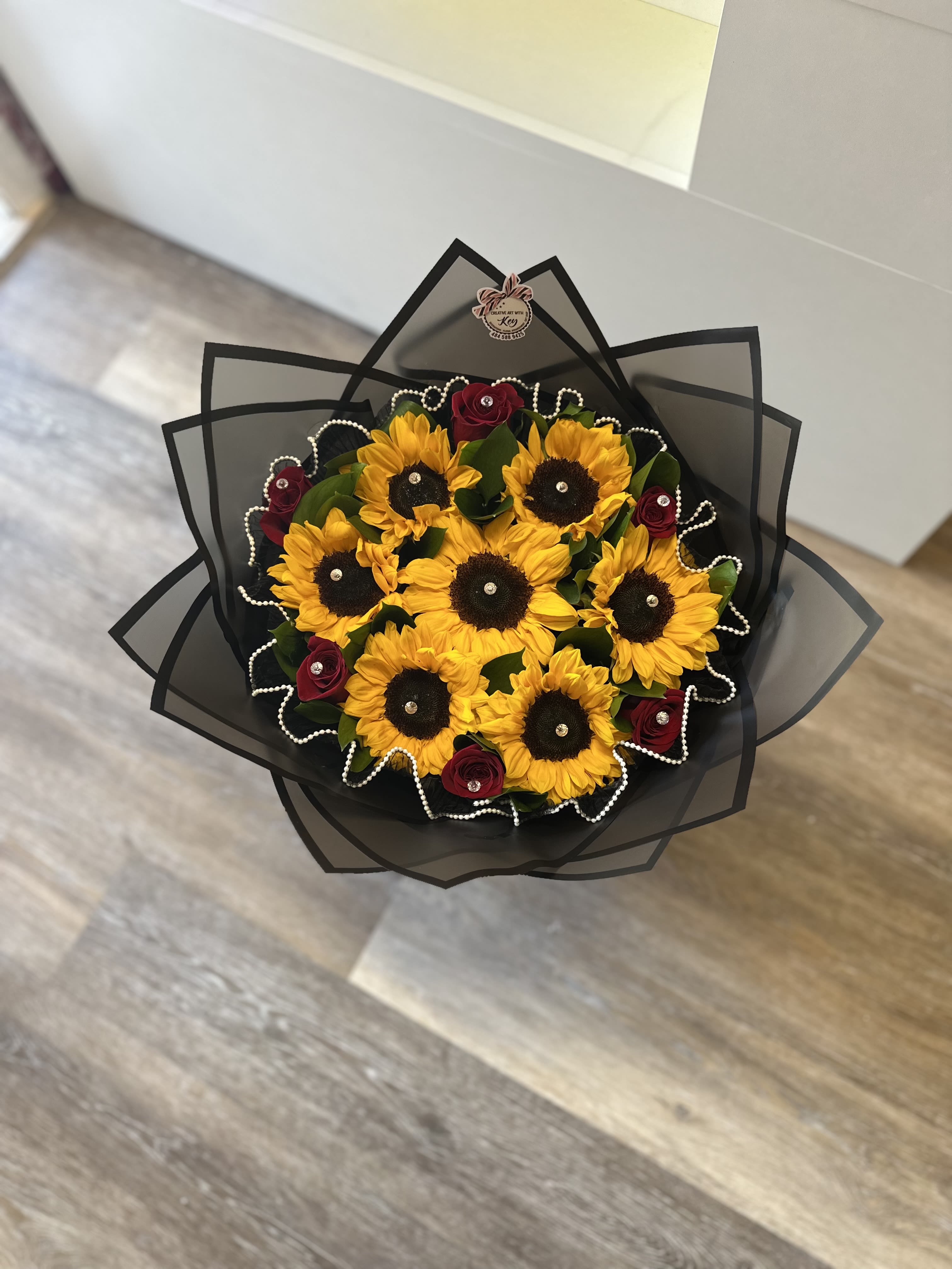 Bouquet of sunflowers and red roses wrapped in black paper