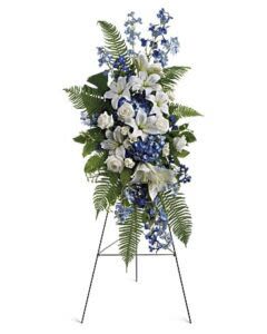 Ocean Breeze blue Spray -  Pet Friendly? No. This arrangement contains white Asiatic lilies, which are highly toxic to cats and can cause kidney failure even in small amounts. Some greenery may also pose risks to household pets.  Keep out of reach; avoid homes with curious cats or dogs who may brush against pollen.   Human Allergy Note : ️ Pollen warning: White Asiatic lilies produce heavy, staining pollen that can trigger allergies and damage clothing. Remove the anthers (brown pollen-covered centers) gently with a tissue upon arrival, or request the florist do so.    Care &amp; Longevity : Your standing spray arrives on an easel with a water-based foam reservoir. Keep the foam consistently moist by adding water daily—pour slowly until the surface feels wet. Avoid direct sunlight, heat vents, and air conditioning drafts.    Why Customers Love It : - Calming color psychology — The blue and white palette naturally soothes grief and evokes peace - Vertical presence — The standing design creates an elegant focal point at services without requiring table space - Fragrant impact — Lily perfume fills a room, creating a memorable sensory tribute - Tropical sophistication — Monstera and exotic ferns add unique texture beyond standard sympathy greens - Ready to display — Includes the easel, so families don’t need to source stands during difficult times   Best Occasions &amp; Situations : - Funeral services and memorials - Sympathy and condolences - Cremation services - Church tributes - Home memorial displays