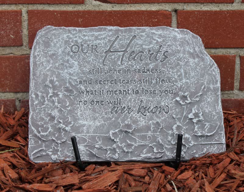 Gray memorial stone with an engraved heart quote on a brick wall