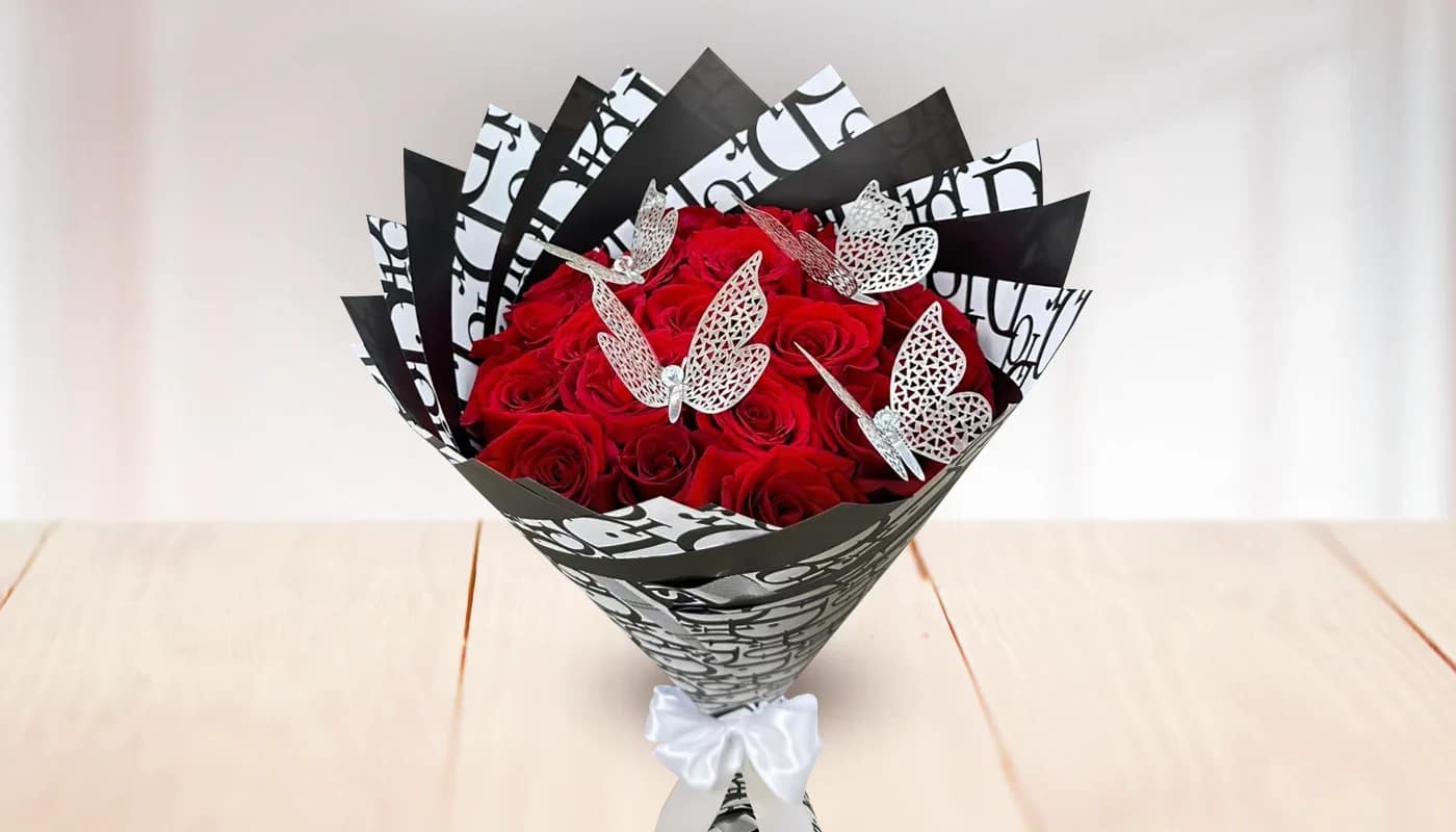 Bouquet of red roses wrapped in black-and-white paper with butterfly accents