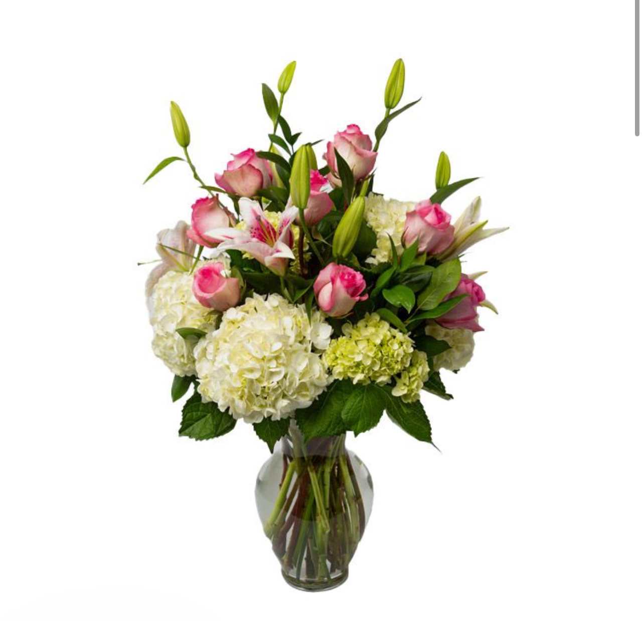 Pink roses and white lilies arranged with hydrangeas in a glass vase