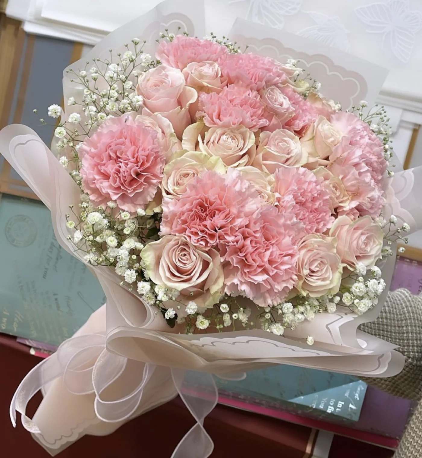 Pink roses and carnations in a wrapped bouquet with baby's breath