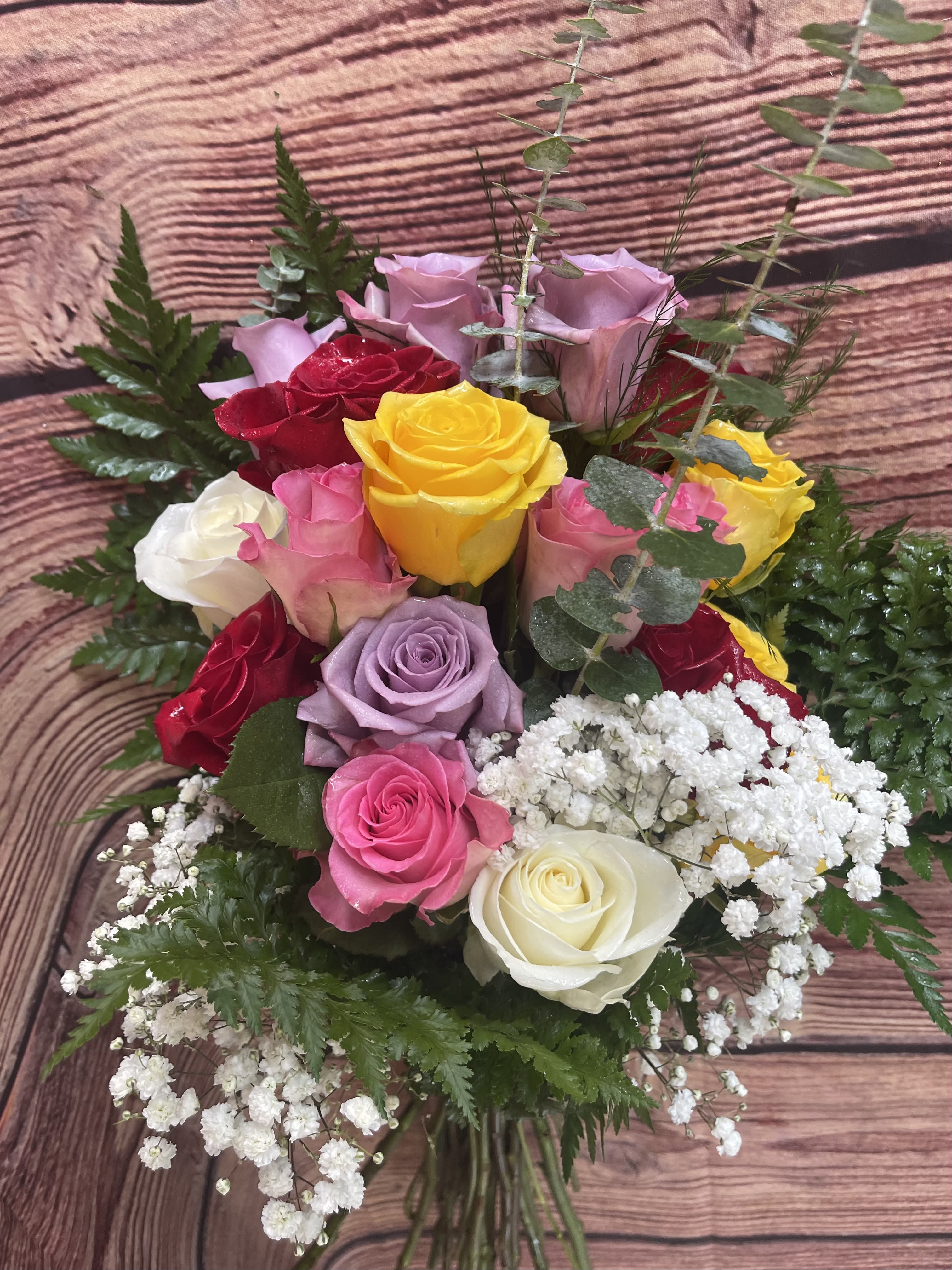 The Color Collection - A presentation of mixed-color roses  with filler and greenery hand tied. The Color Collection is delivered wrapped and tied with a bow. Perfect to congratulate and honor achievements! An excellent choice for Dance Revue, Graduation, Recital, Bravo!