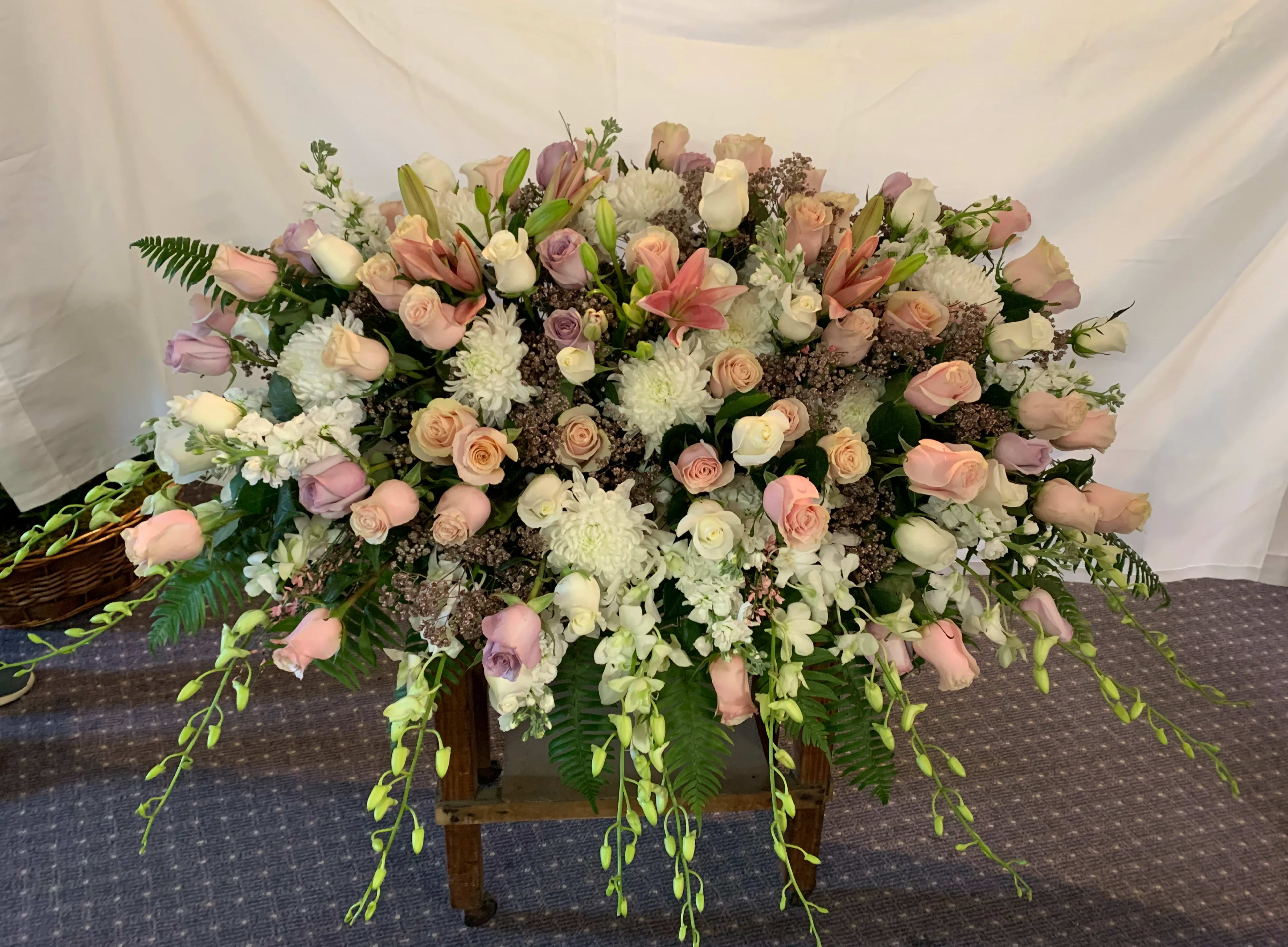 Large pastel floral spray with roses, lilies, and white blooms on a stand