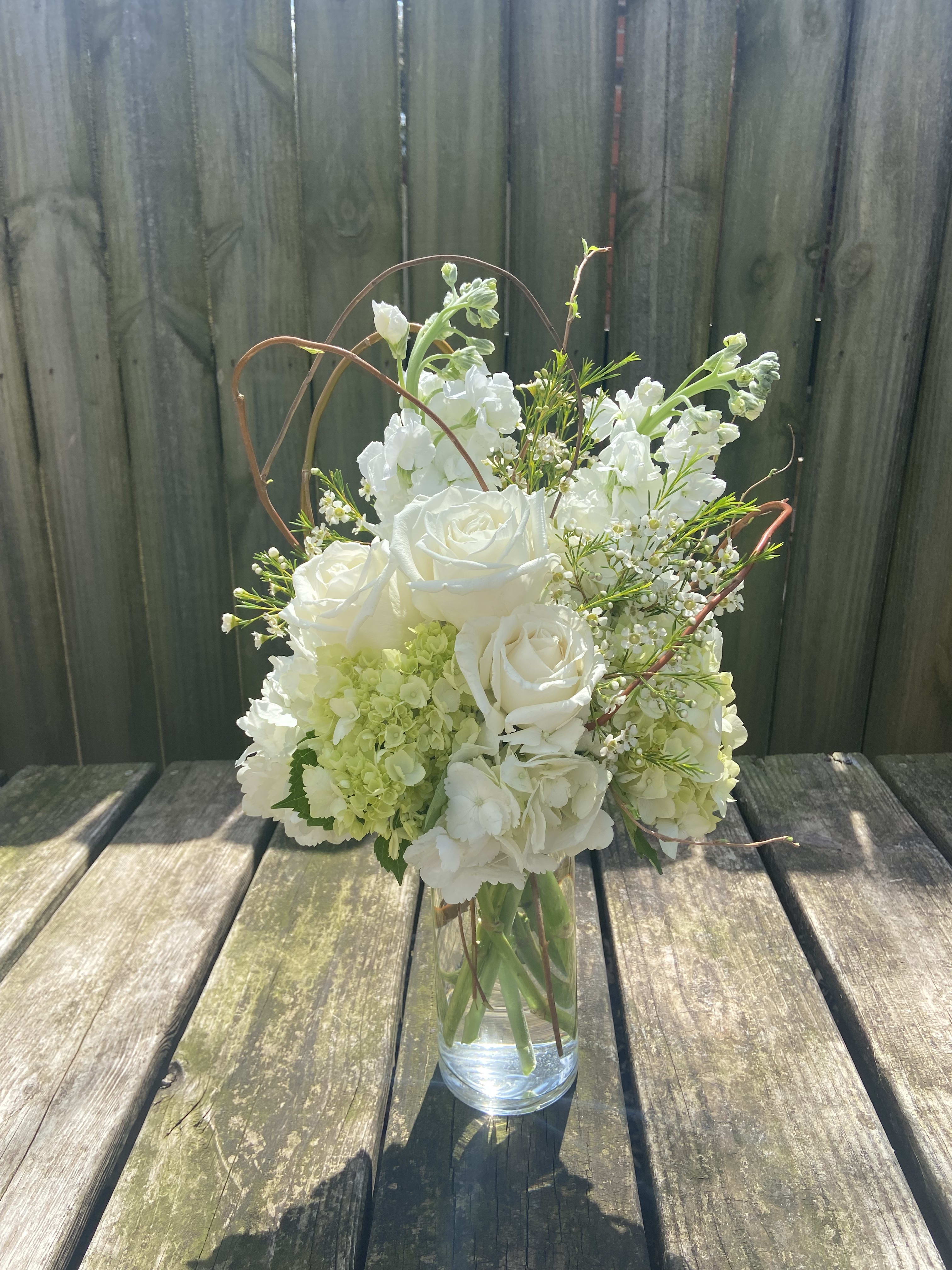White roses and hydrangeas arranged in a clear glass vase