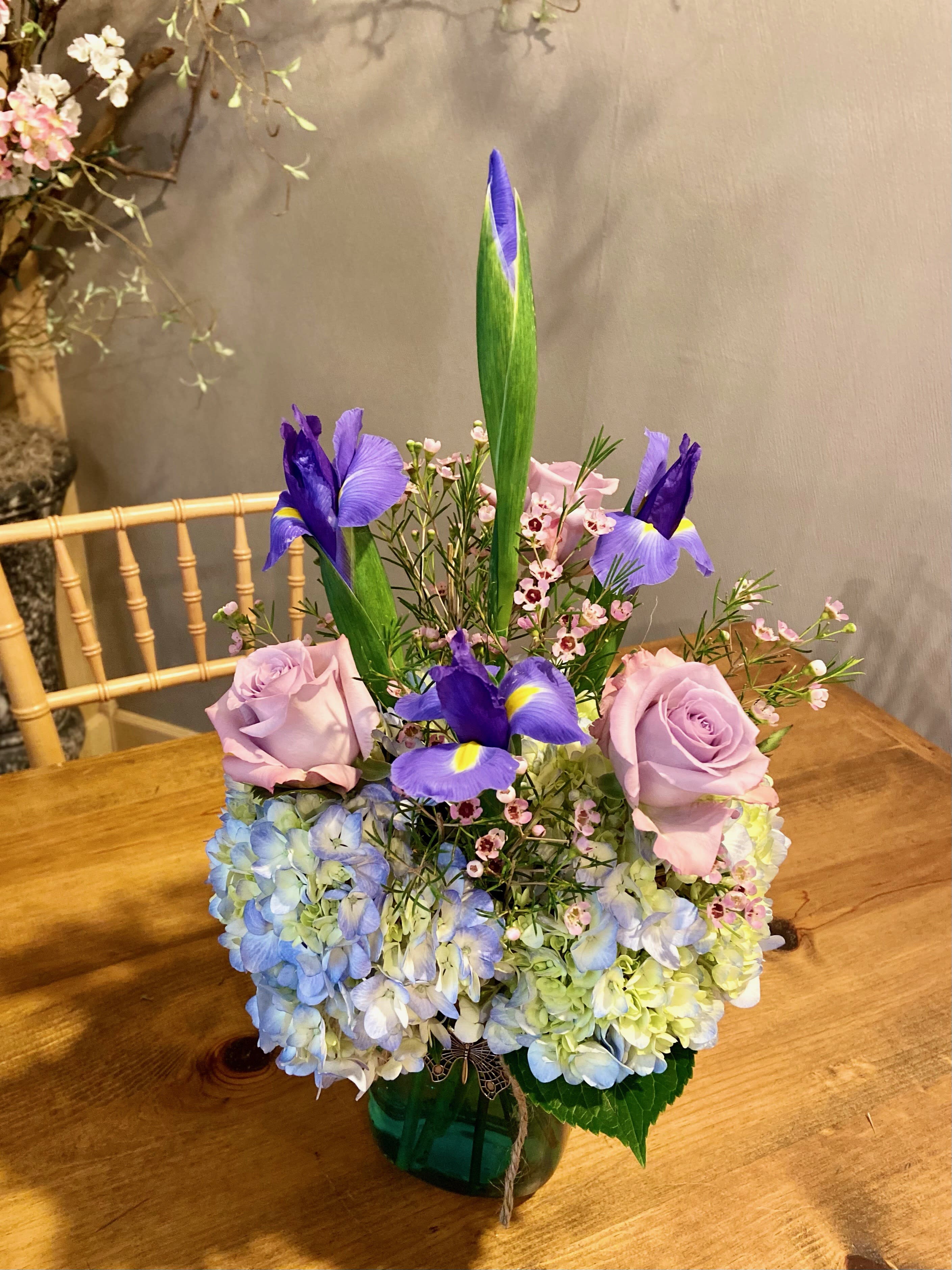 Bouquet of lavender roses, blue hydrangeas, and purple irises in a vase
