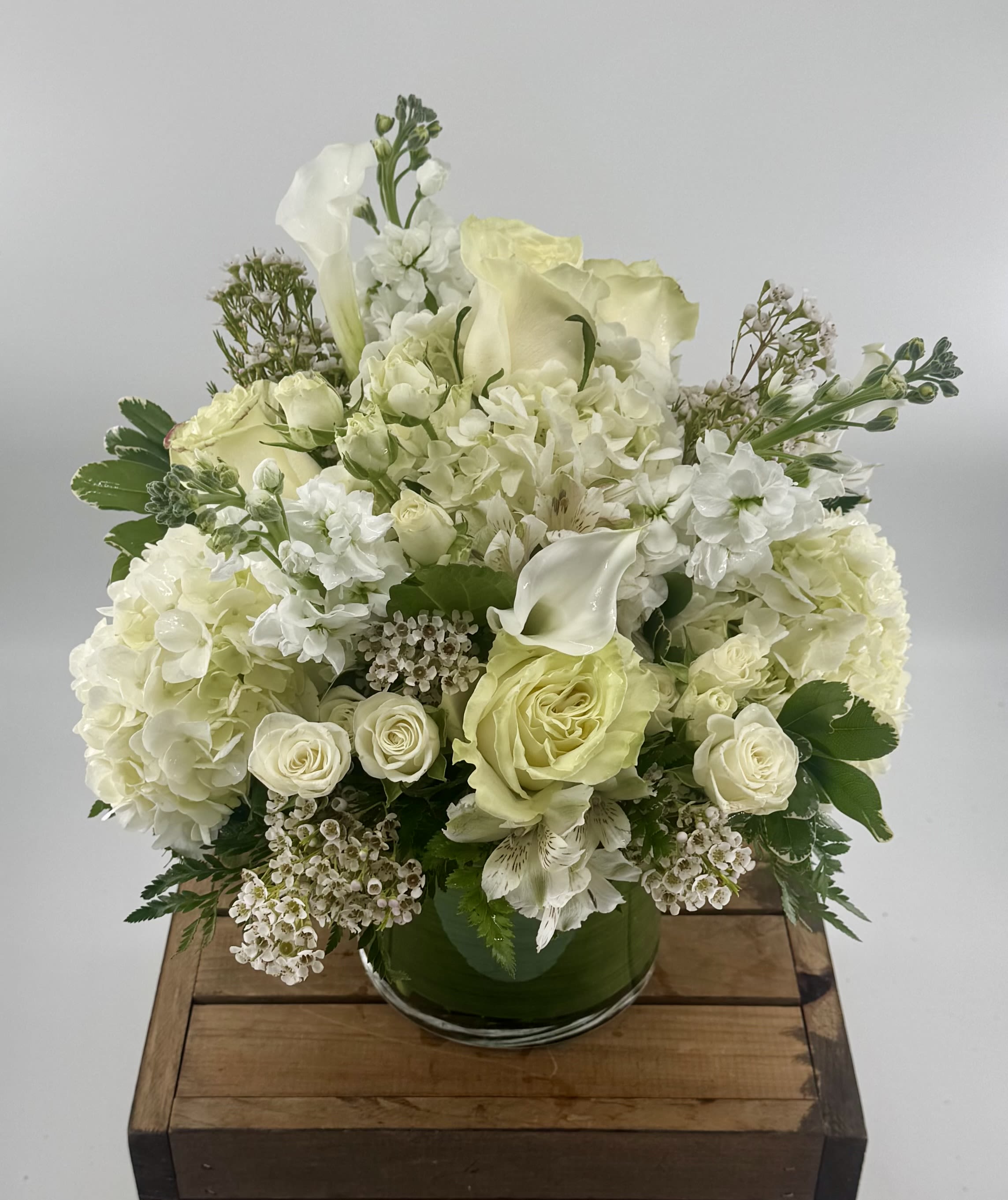 Vanilla Blossom (BR) - Indulge in the delicate beauty of the "Vanilla Blossom" arrangement, a luxurious combination of white hydrangeas, white roses, white stock, spray roses, wax flower, and white mini calla lilies. This stunning bouquet is expertly crafted to evoke a sense of elegance, purity, and tranquility.