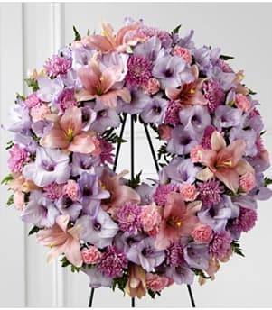 Lavender and pink floral wreath with lilies and carnations on a black easel