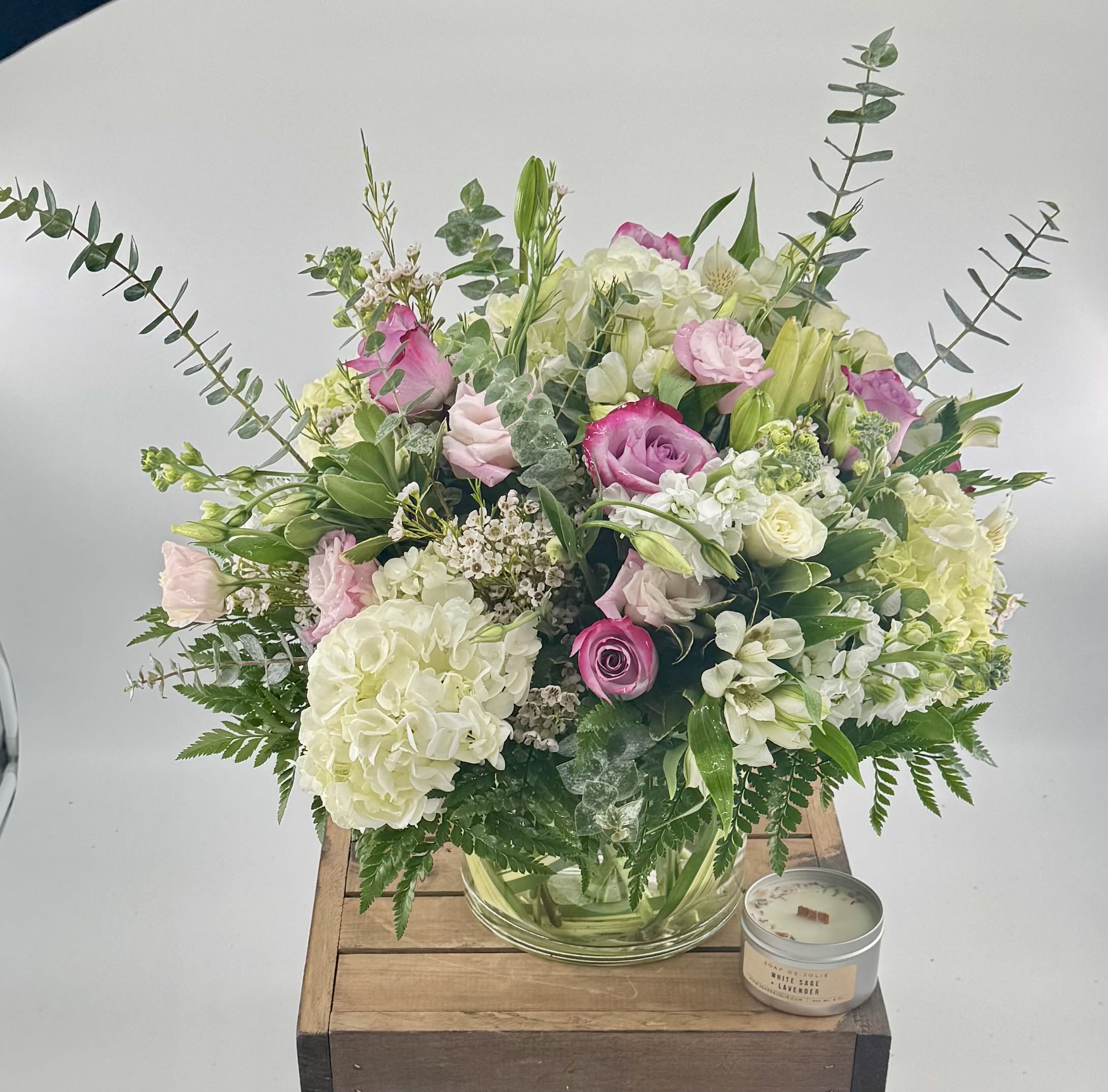 Paradise  (BR) - Elevate your special moments with this modern arrangement of roses, hydrangea, white stock, and pink lisianthus, accented by delicate wax flowers and soothing eucalyptus. Expertly crafted in a 7x7" glass cylinder vase, it’s a timeless expression of care and elegance. 