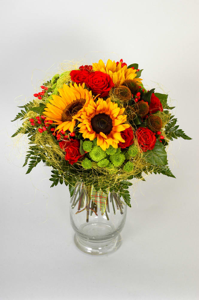 Bright bouquet with sunflowers, red roses, and green mums in a clear glass vase