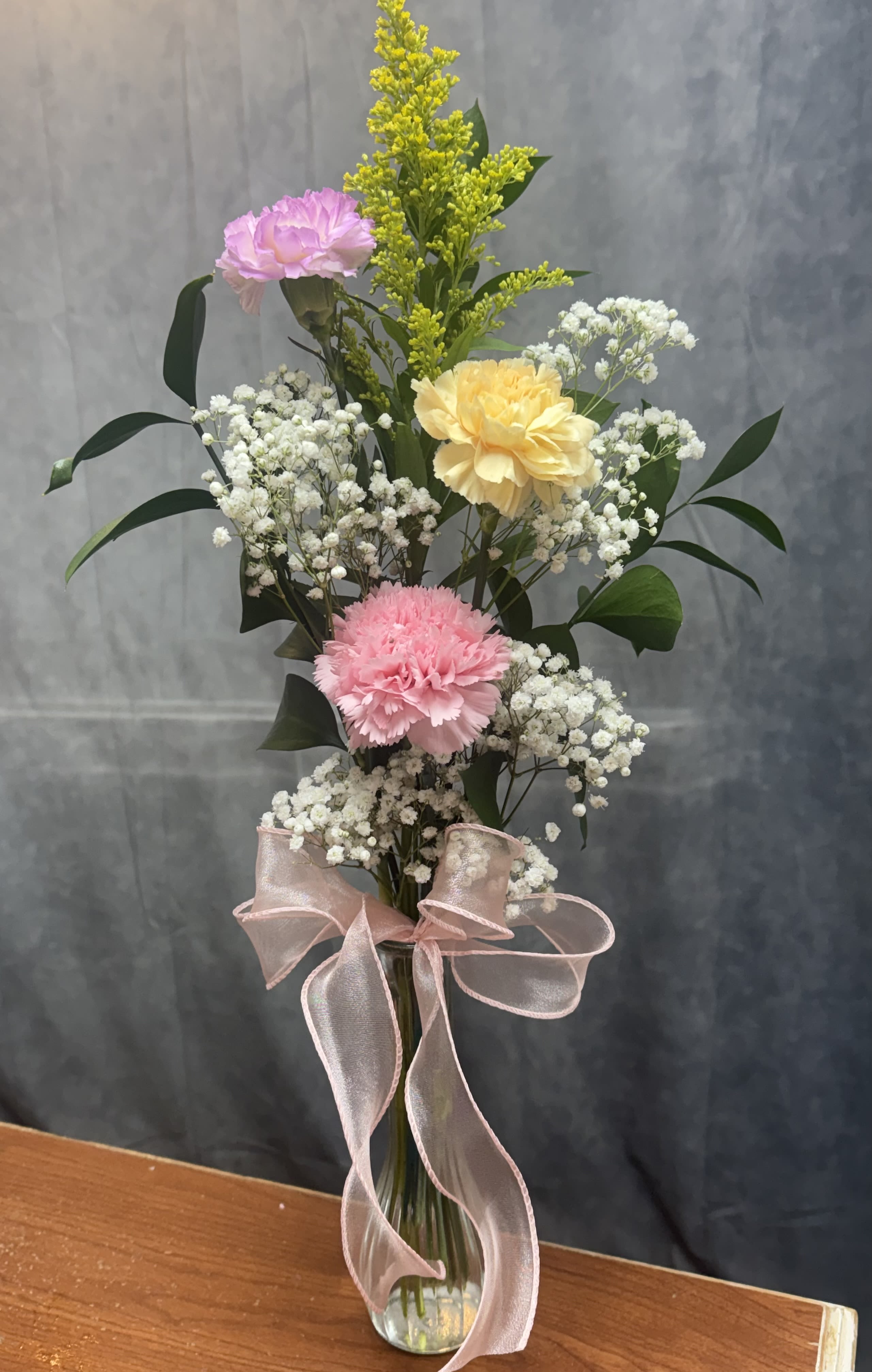 Pink and yellow carnations with white baby's breath in a glass vase