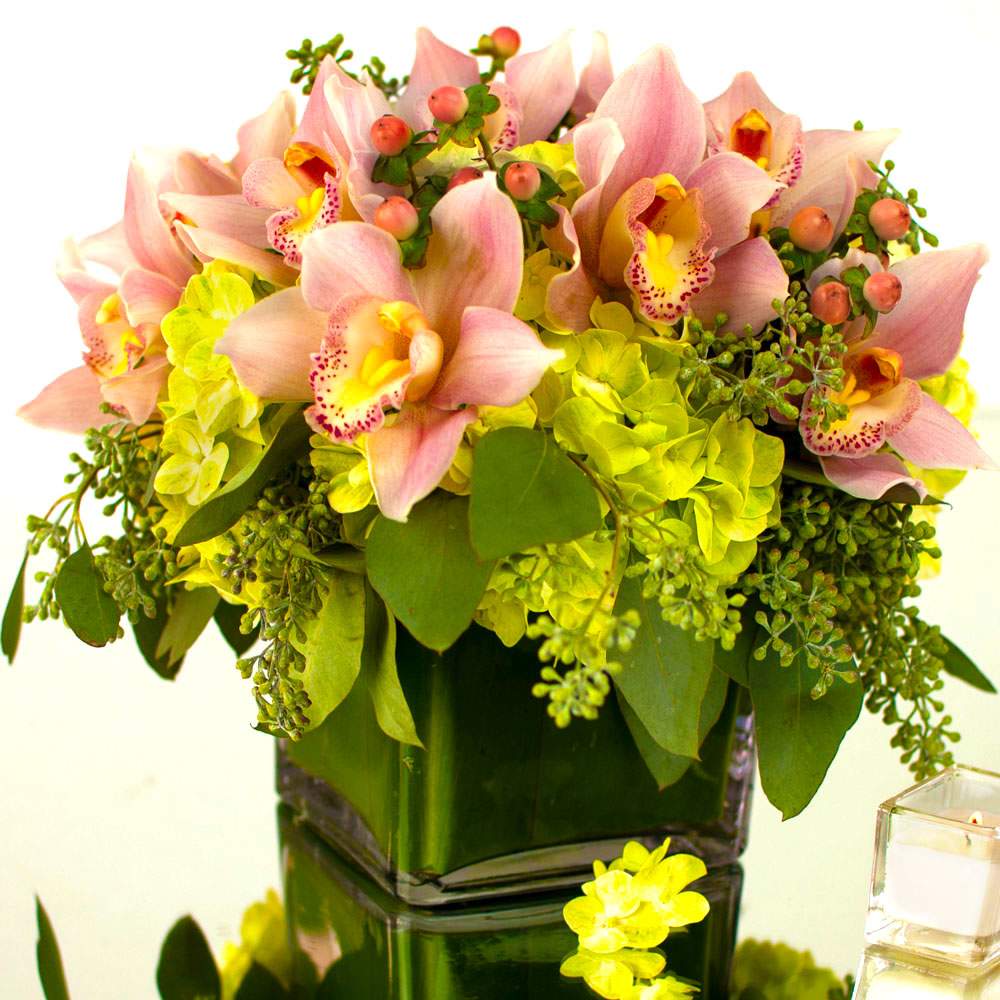 Bright Sunset (DL) - Our stunning and showy modern Bright Sunset flower arrangement is a true feast for the eyes, filled with the vibrant colors and unique textures of green hydrangea, cymbidium orchids, hypericum berries, and seeded eucalyptus. This captivating combination creates a mesmerizing effect that exudes charm, elegance, and sophistication.  