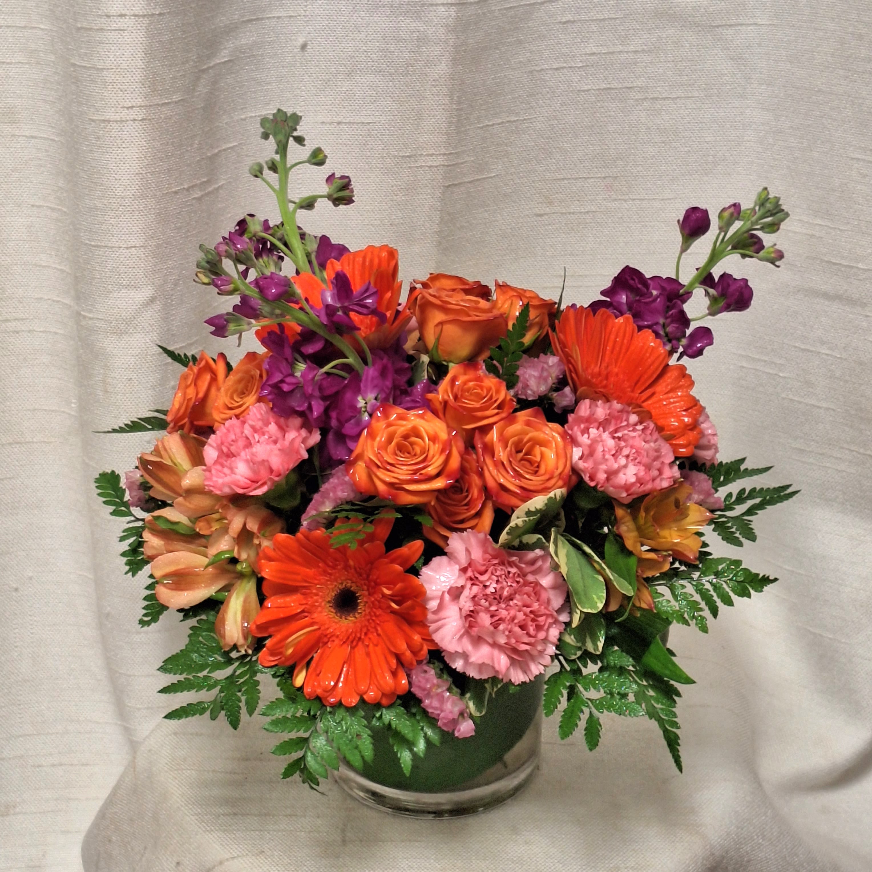 Festive Fiesta (BB) - Get ready to add a burst of vibrant energy to any occasion with our "Festive Fiesta" floral arrangement. This arrangement is an exciting blend of bright and bold colors, featuring hot pink roses, carnations, orange gerbera daisies, and spray roses.