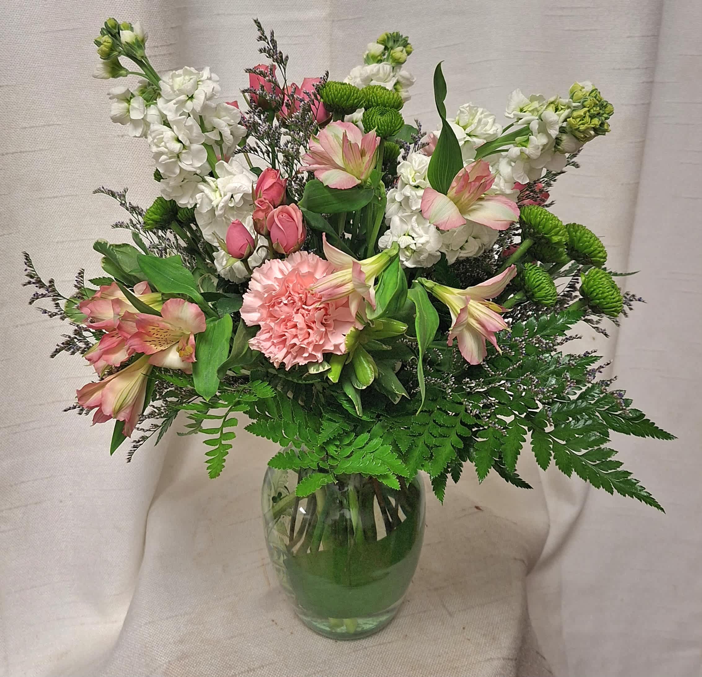 Everlasting Happiness (DL) - Our charming Everlasting Happiness flower arrangement in a delicate glass vase is a beautiful ensemble of pink roses, pink alstroemeria, green button poms, and pink carnations. This delightful combination creates a harmonious display of soft colors and gentle textures, perfect for conveying love, appreciation, or simply brightening someone's day.  