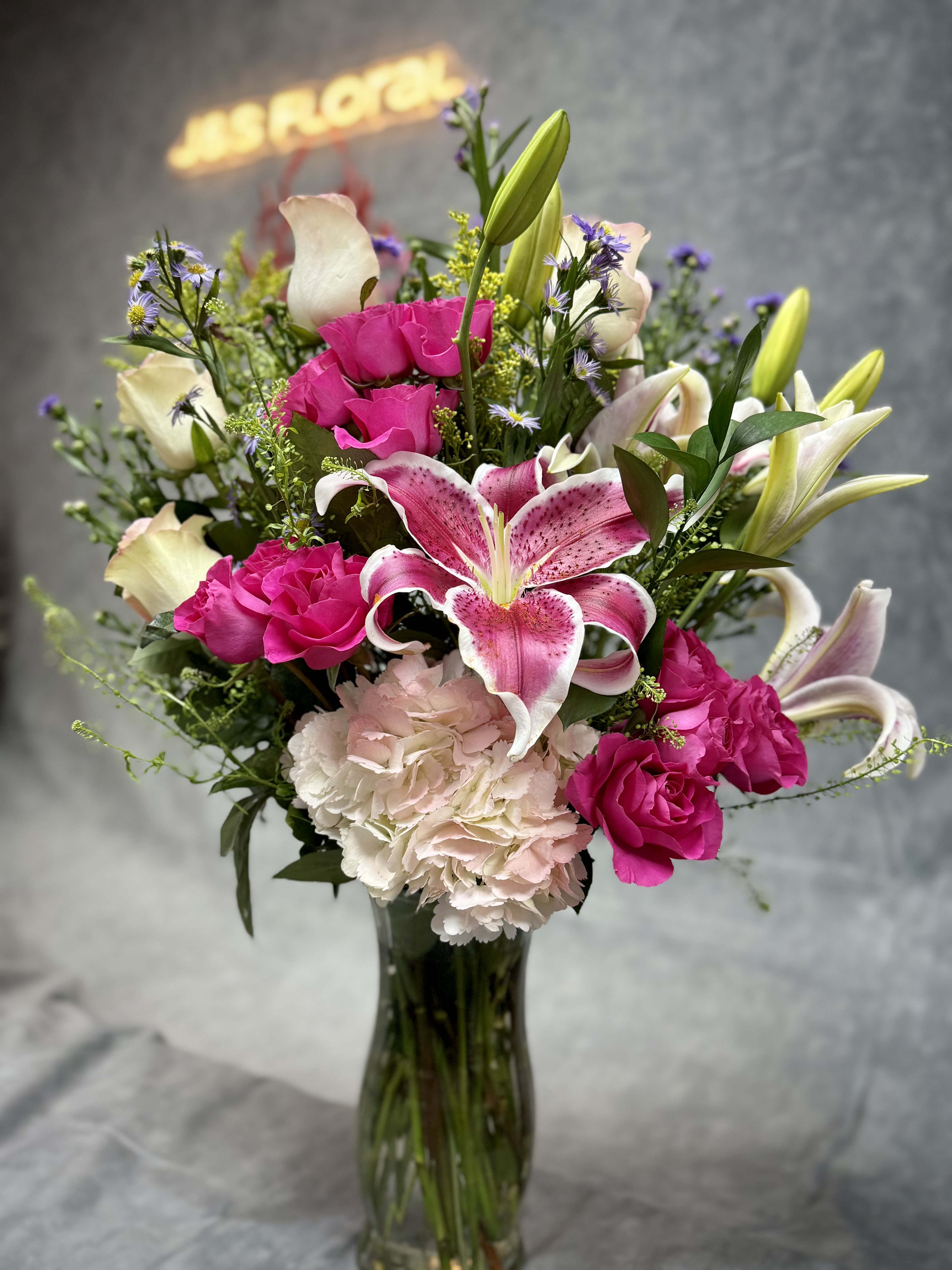 Pink lilies, roses, and carnations in a glass vase