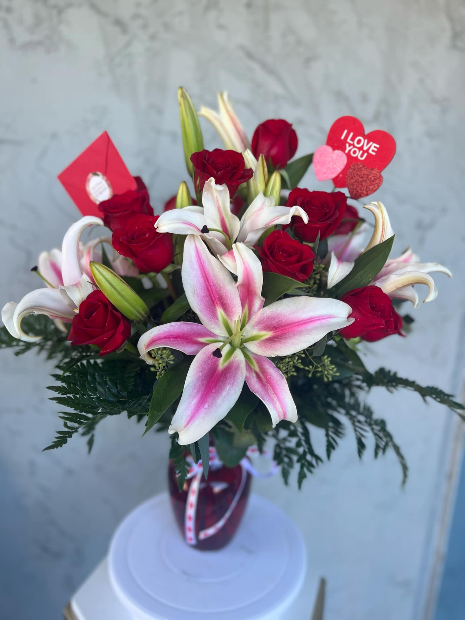 Bouquet of red roses and pink-white lilies in a vase with Valentine hearts