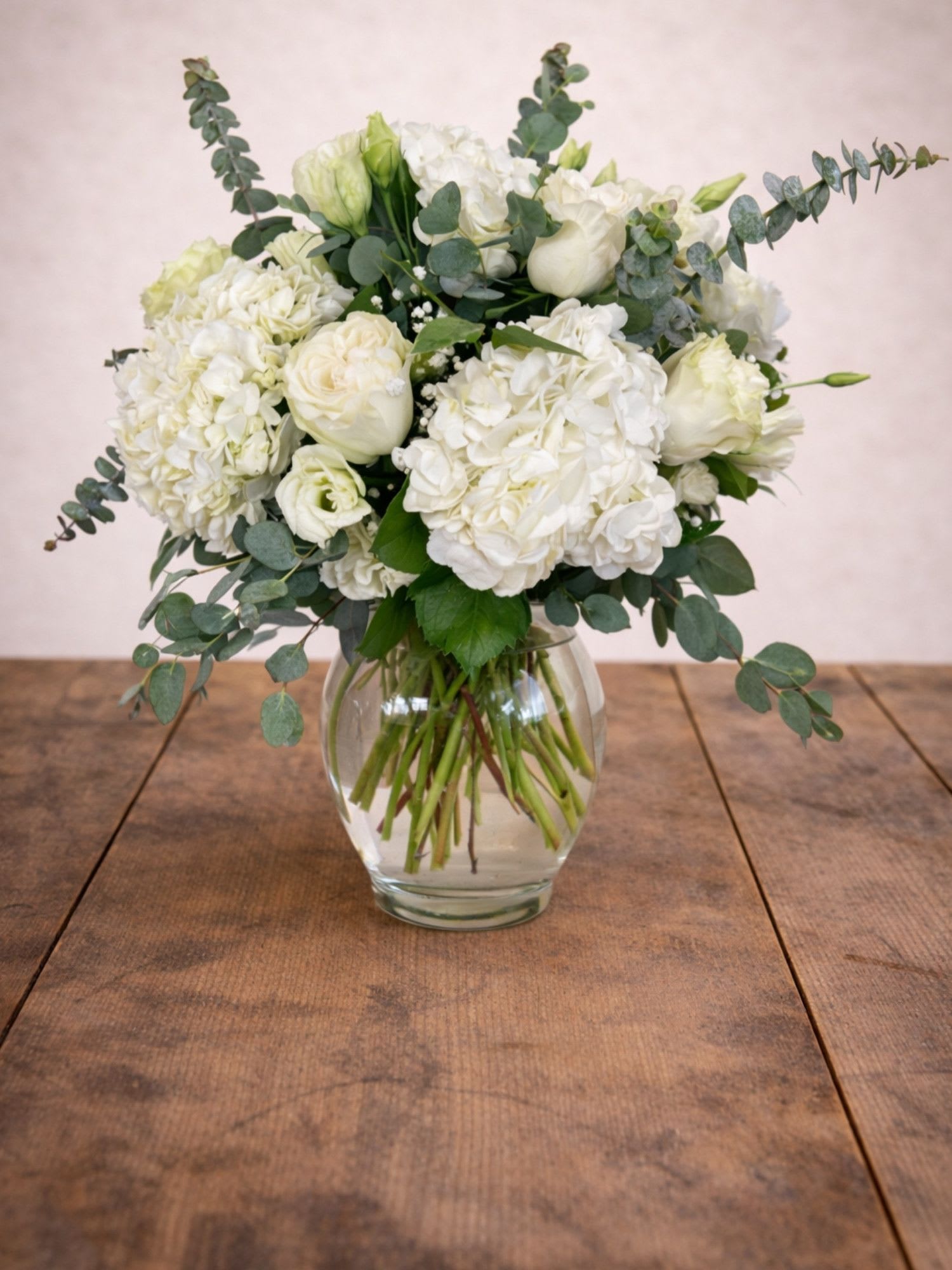 White hydrangea and rose bouquet in a clear glass vase