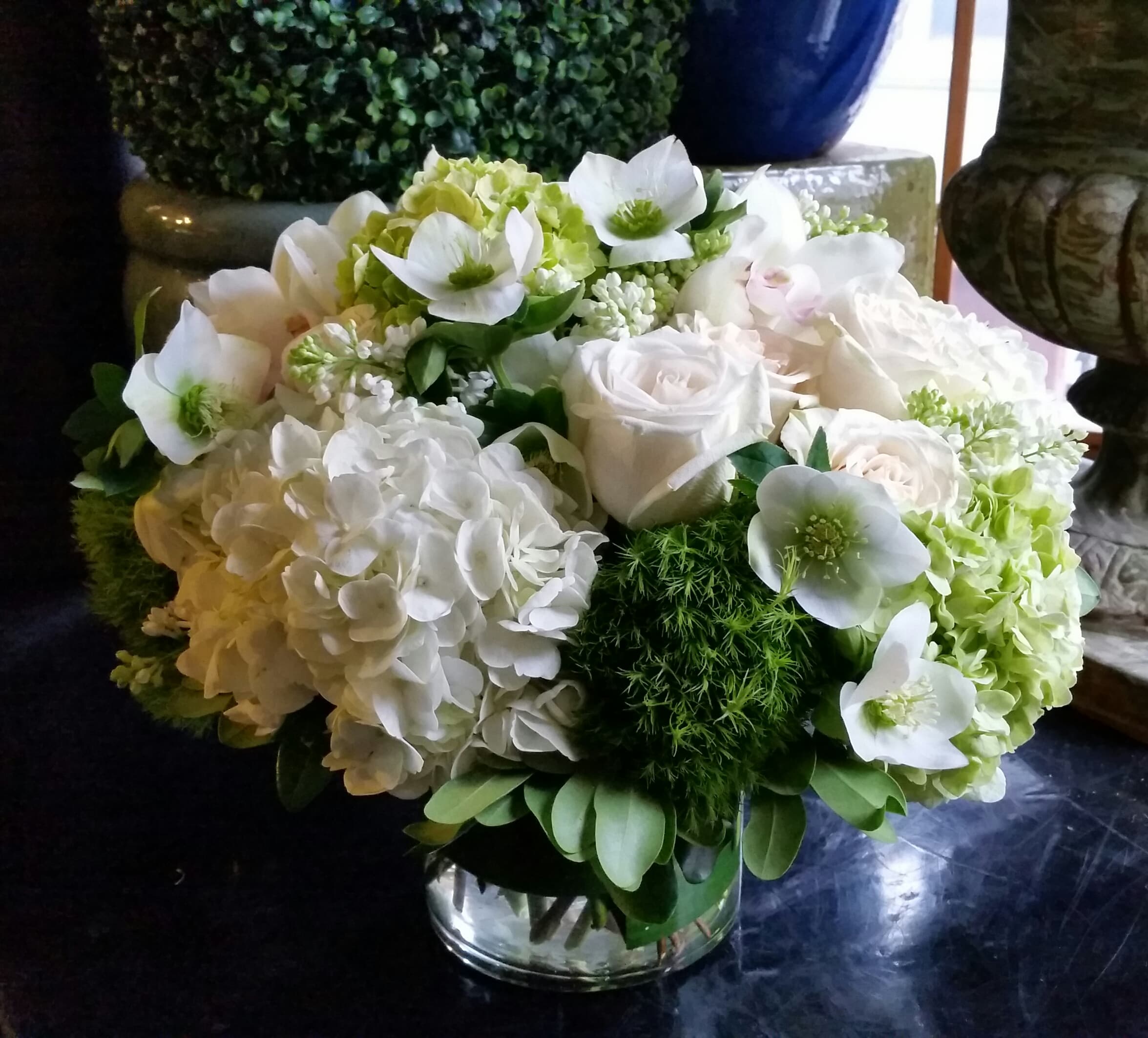 White floral arrangement in a clear glass vase with hydrangeas and roses