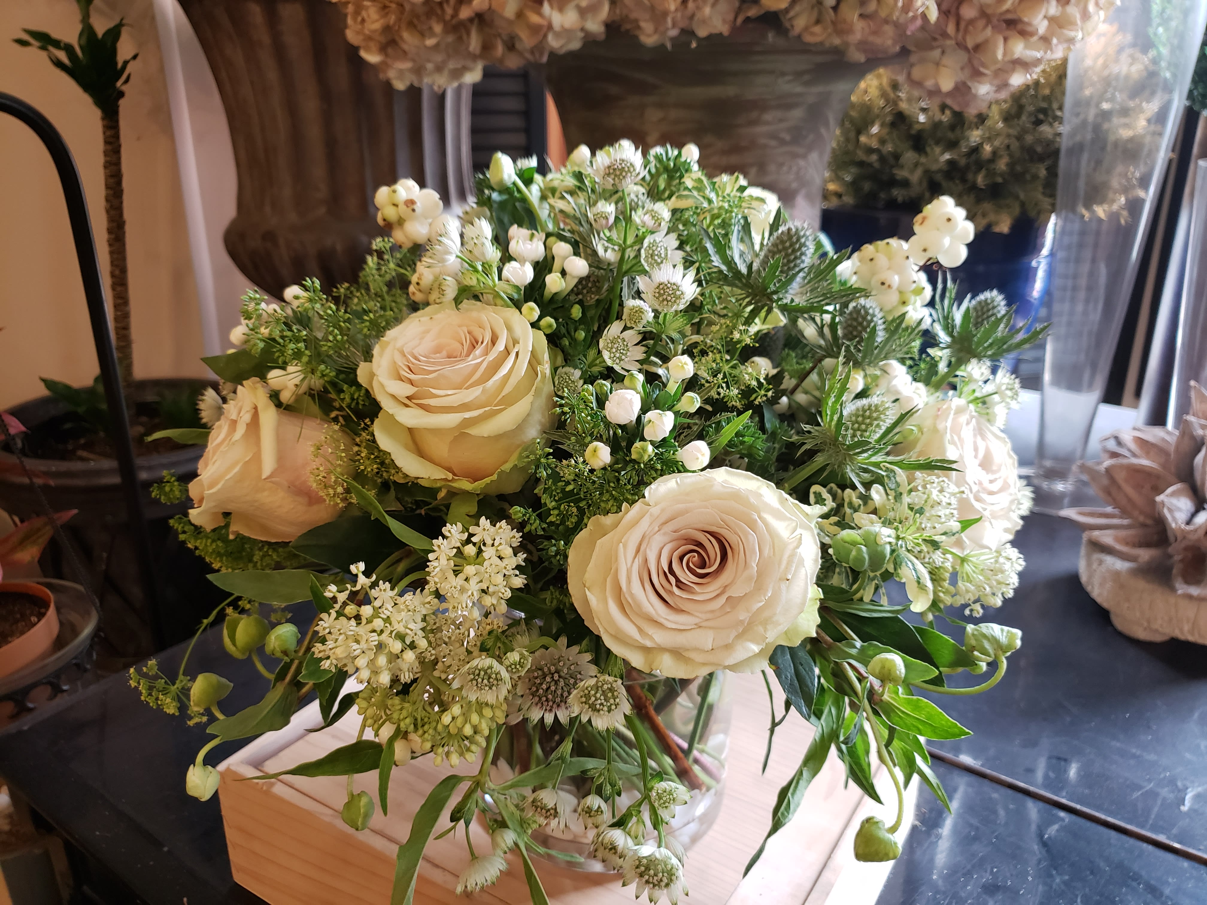 Cream roses arranged in a clear glass vase with white filler flowers